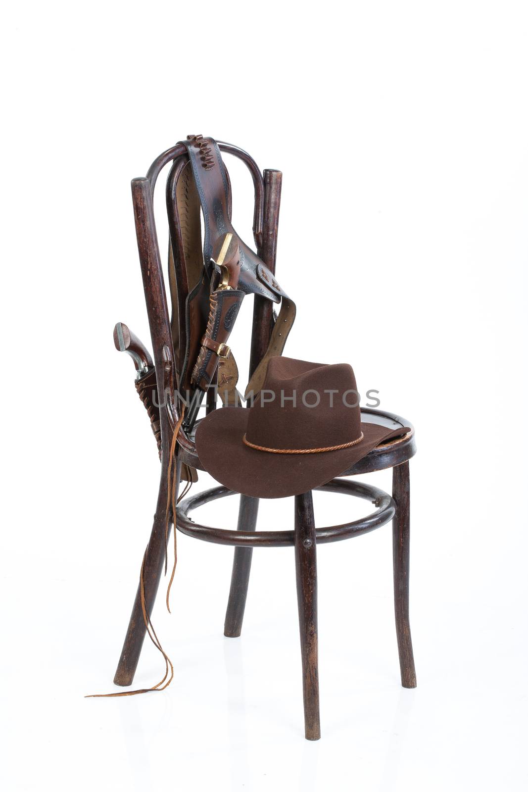 Cowboy belt, guns and hat on an old chair on isolated background