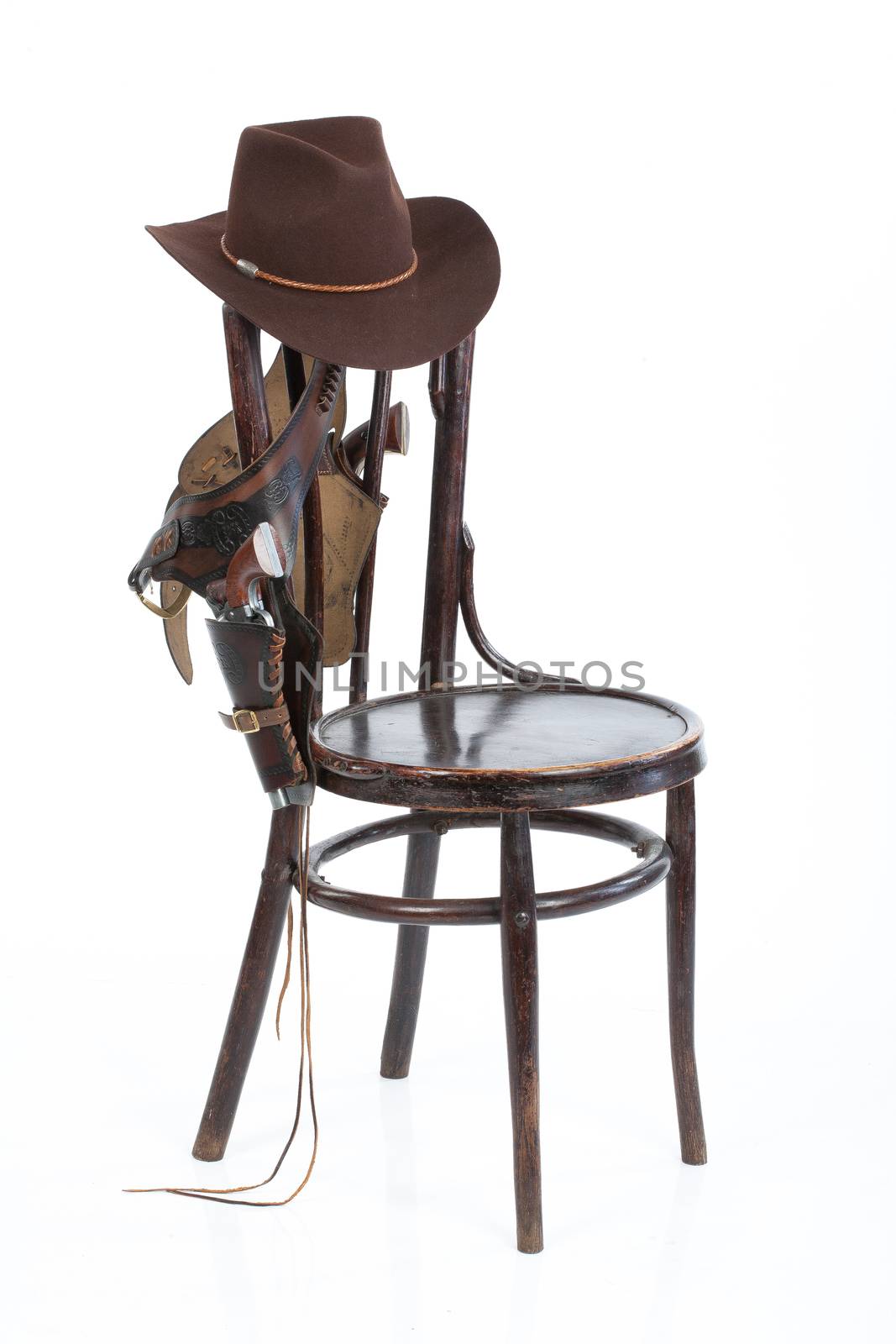 Cowboy belt, guns and hat on an old chair on isolated background