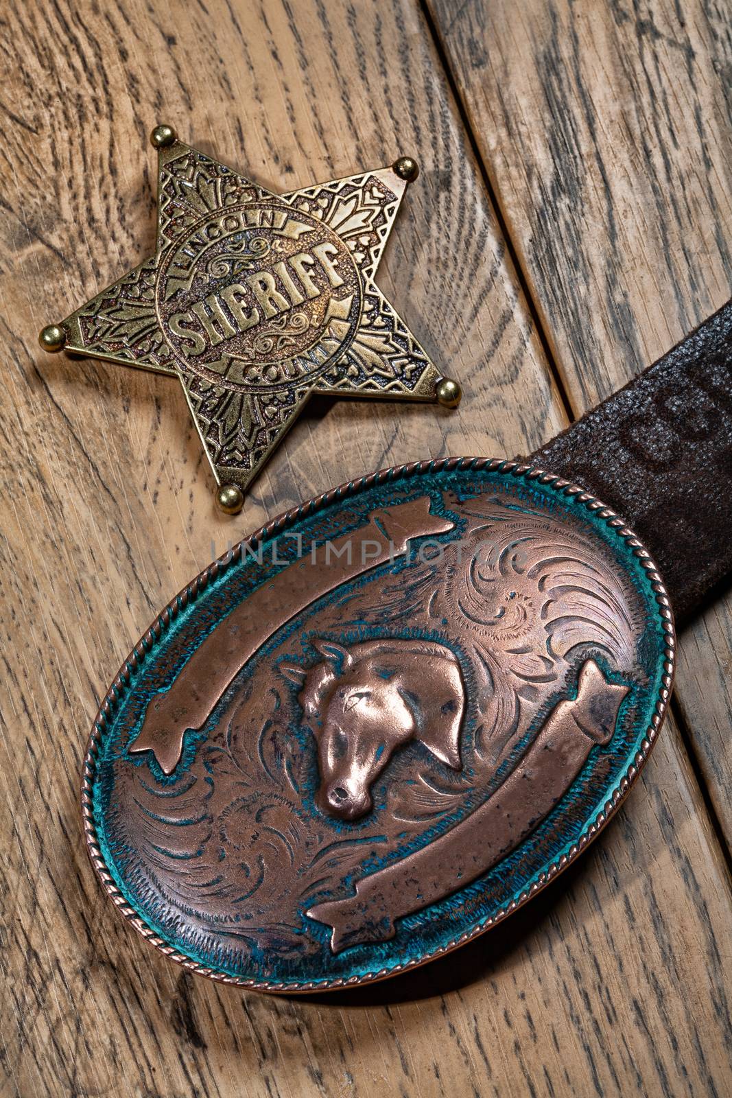 Sheriff's star and copper buckle on a wooden background