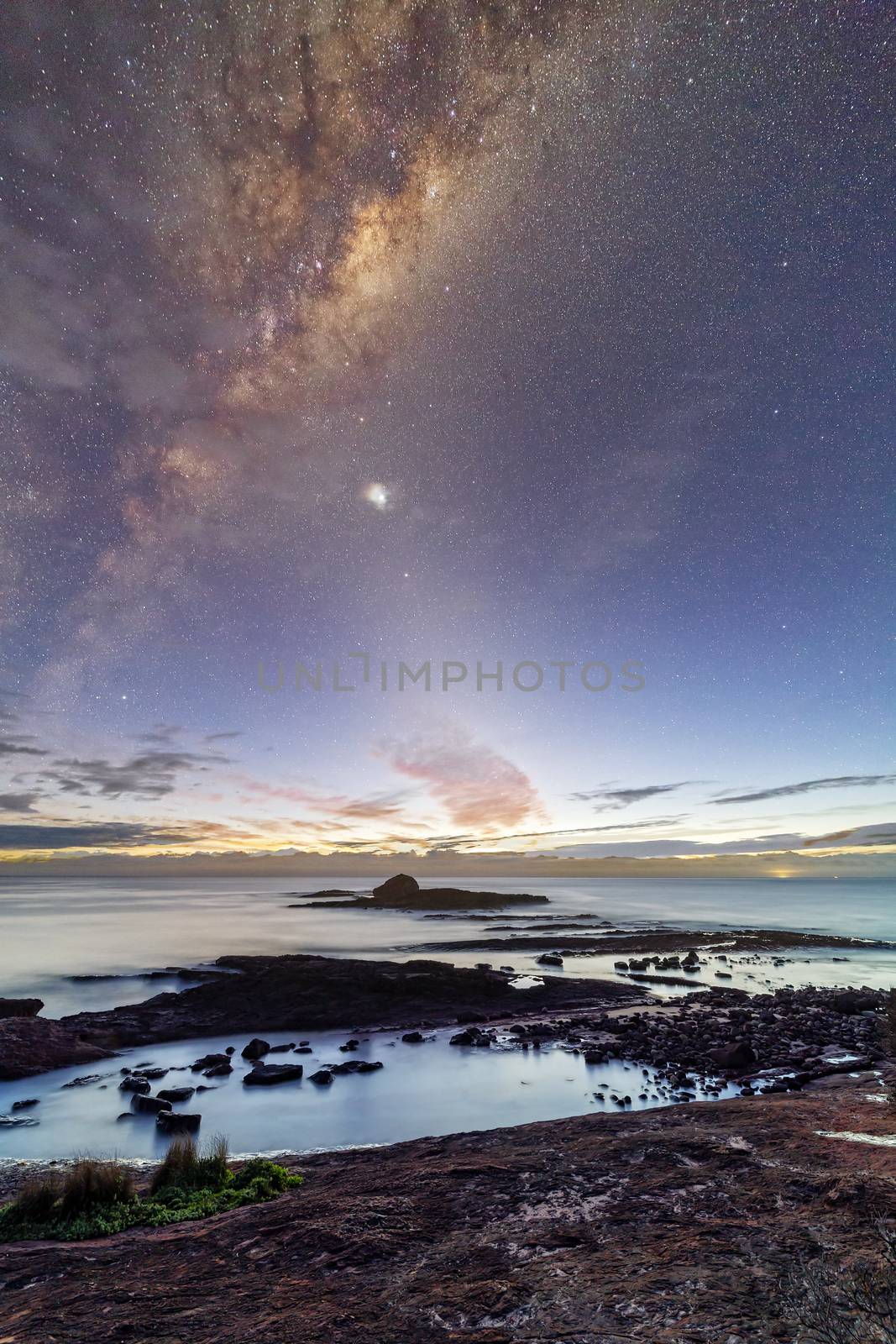 Starry night sky and milky way setting over the coast of Haycock Point in Ben Boyd National Park, Australia
