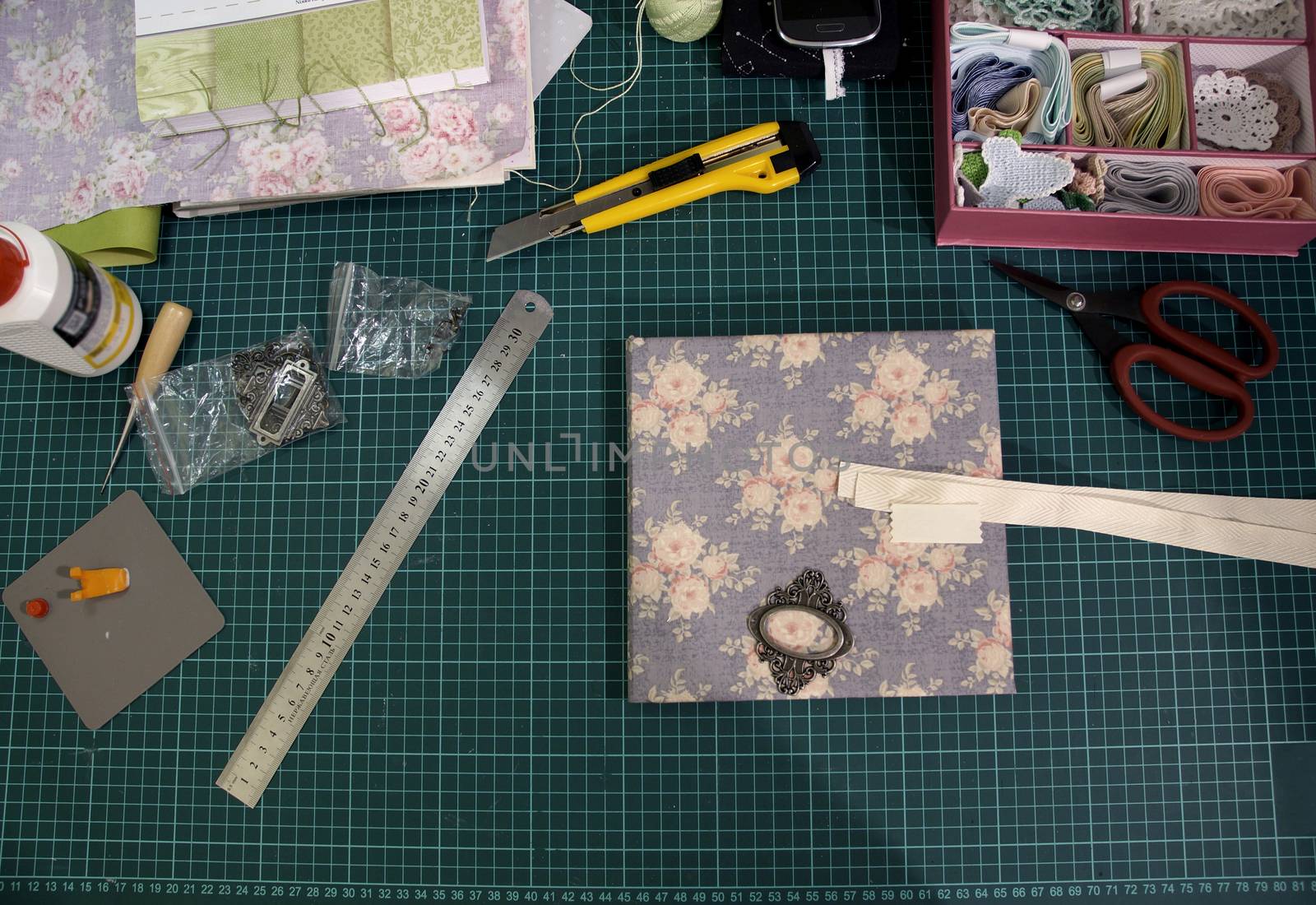 the process of handmade creating of the diary from special scrapbooking paper, paper flowers and other decorative elements