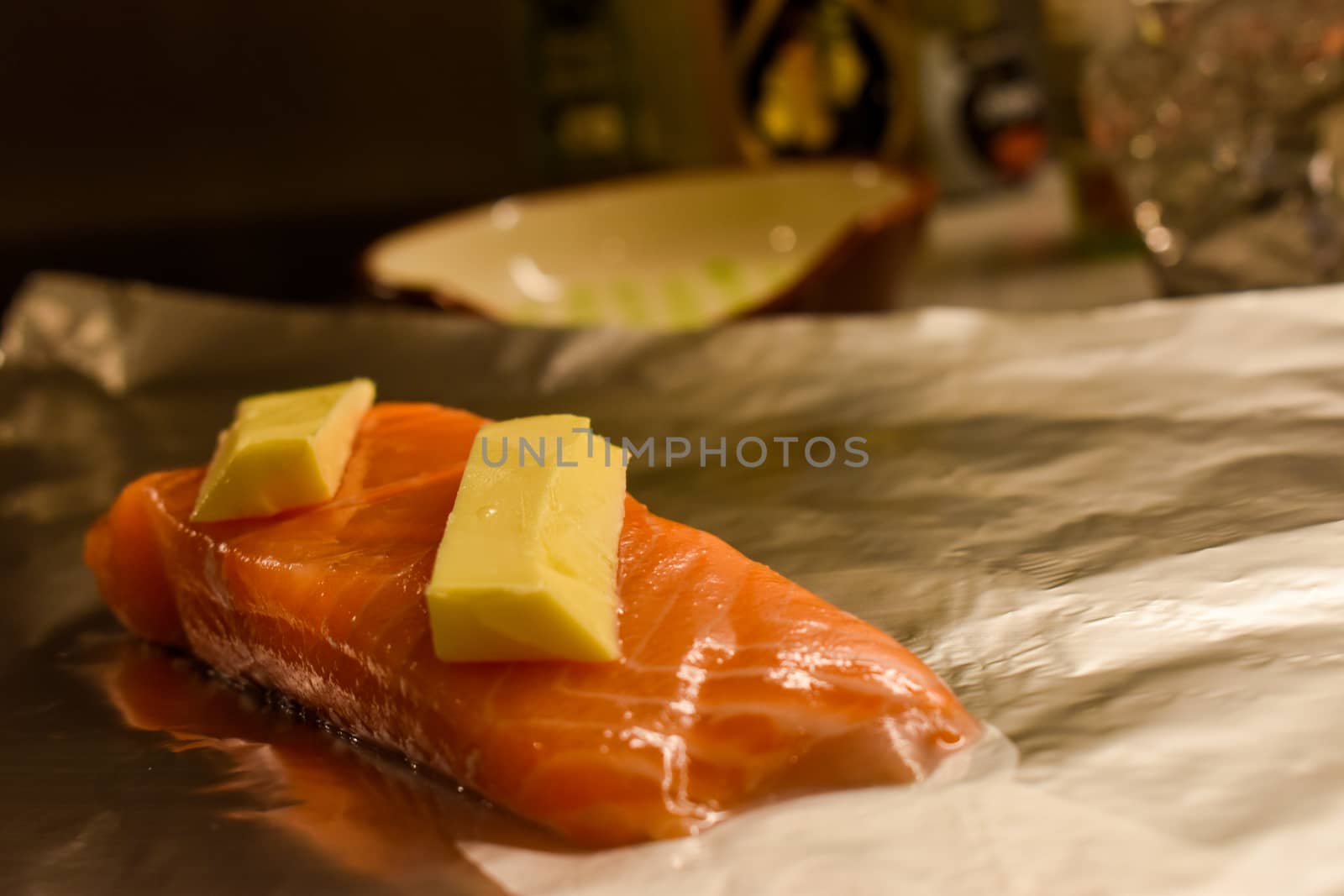 A close up of an organic salmon darne on tinfoil being prepped with butter