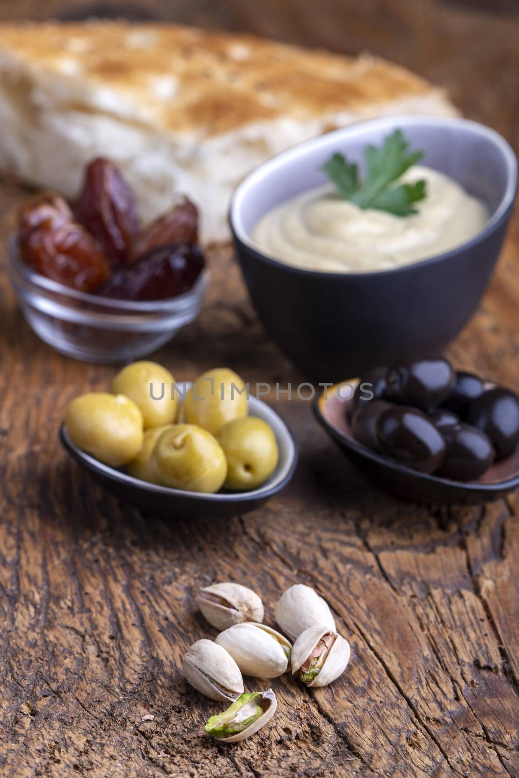 olives and hummus on dark wood by bernjuer