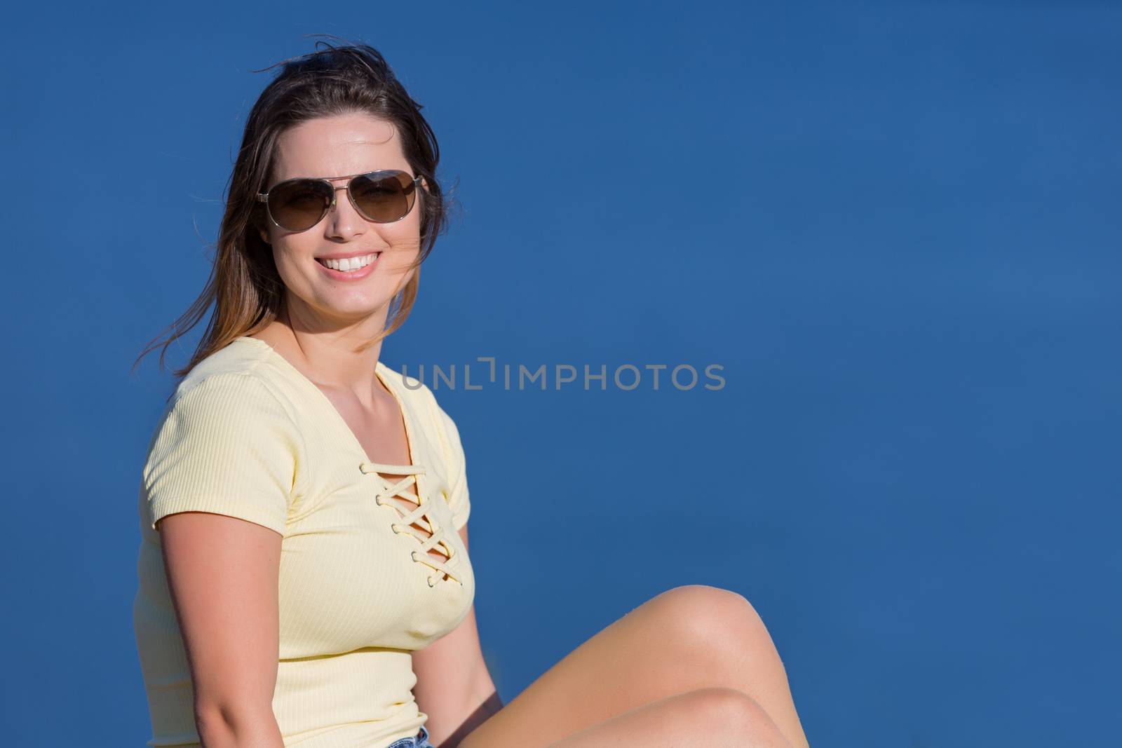 Young happy woman sitting on the rock mountain, relaxing and enjoying the lake at Geres, Portuguese National Park