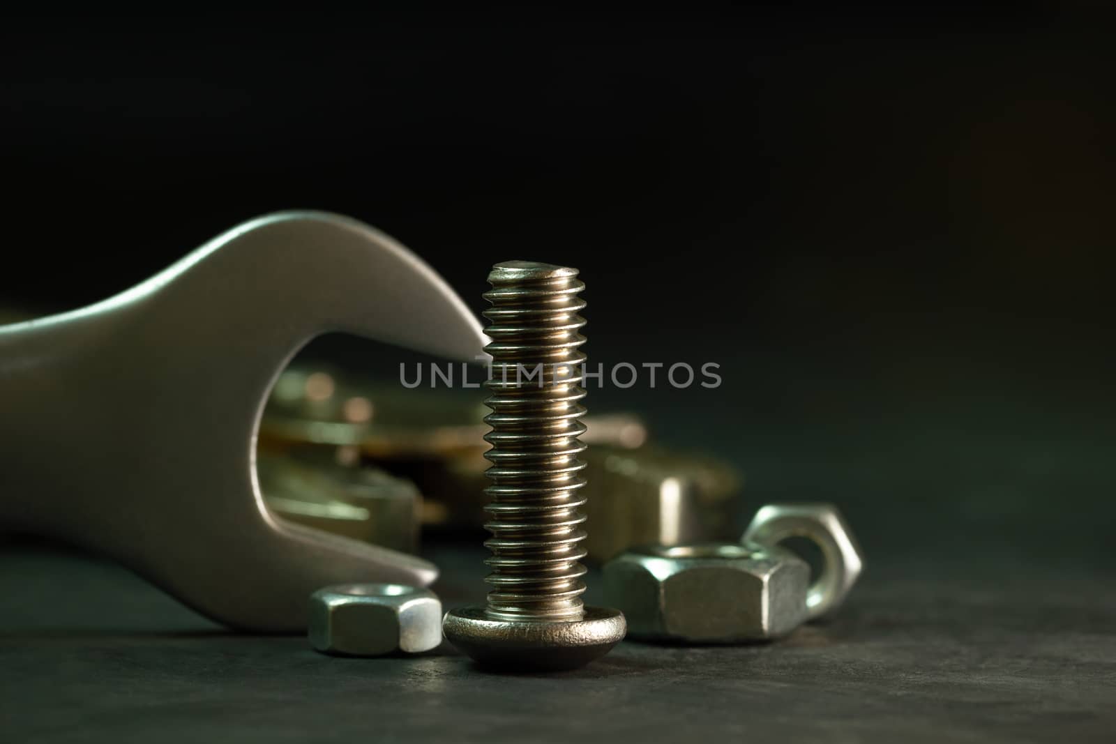 Bolt nuts and wrench on cement floor in darkness. Closeup and copy space for text. Concept of mechanical engineering jobs.