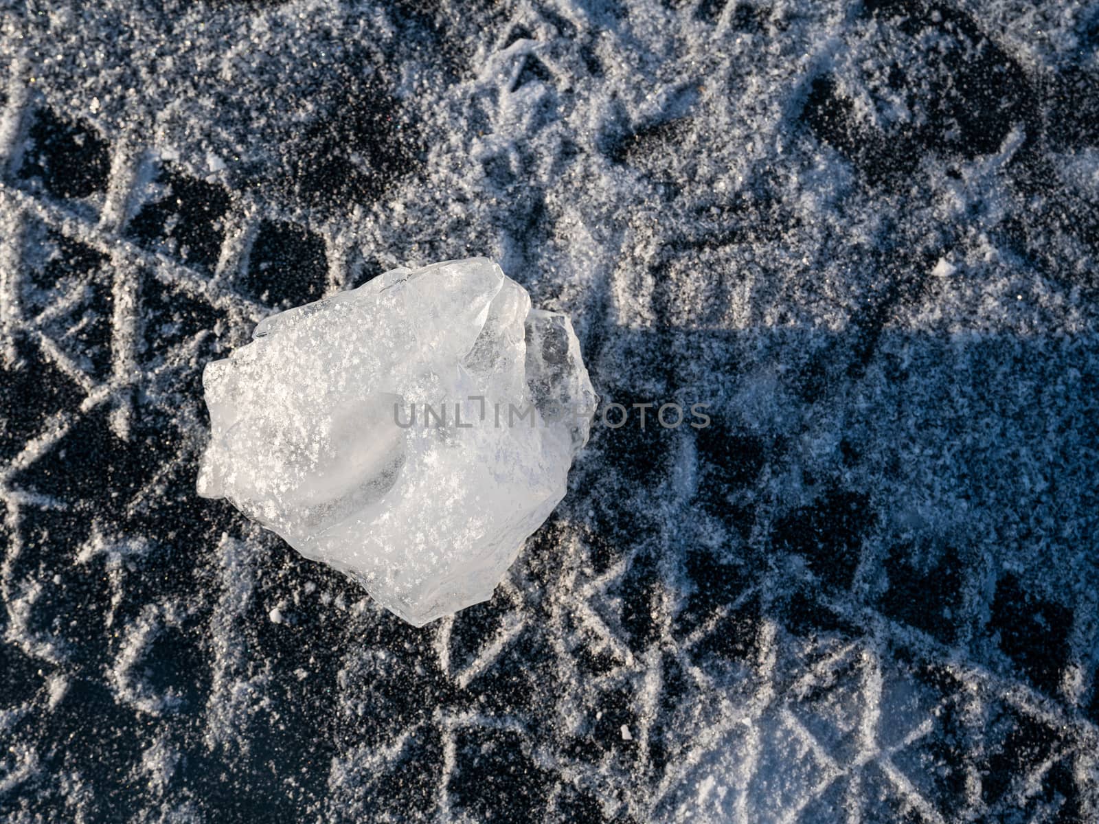 Closeup unusual shapes ice cube on the frozen lake surface. Tire tracks run on snow-covered areas. Lake Baikal, Russia