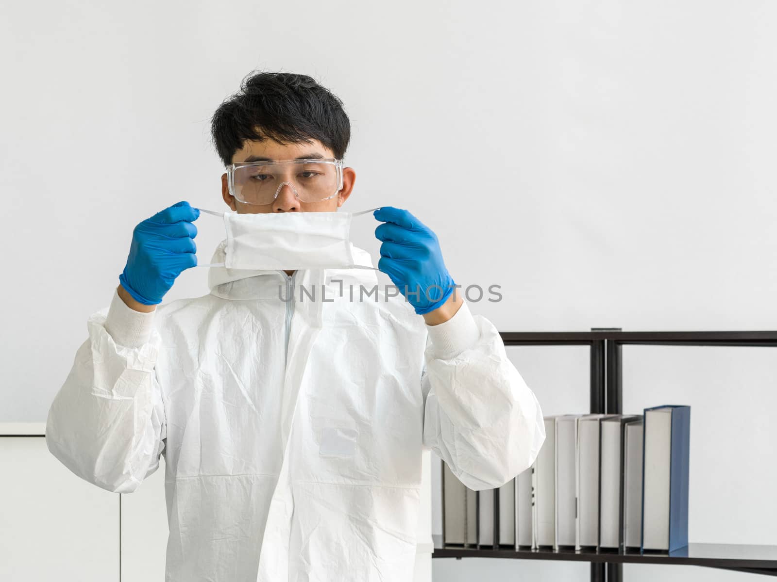Asian scientists inspect the quality of a mask before beginning the experiment in a scientific laboratory.