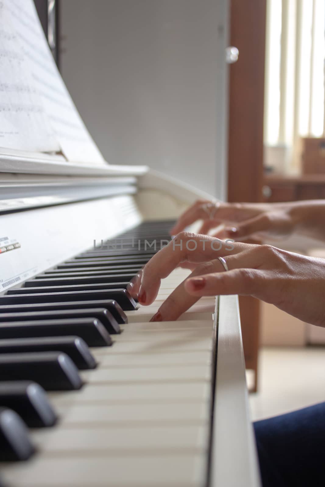 Woman practicing lessons on her white electric piano