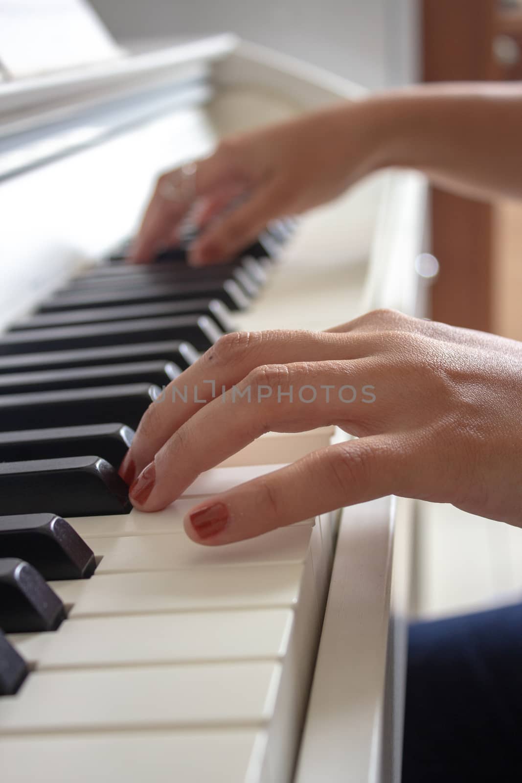 Woman practicing lessons on her white electric piano by etcho