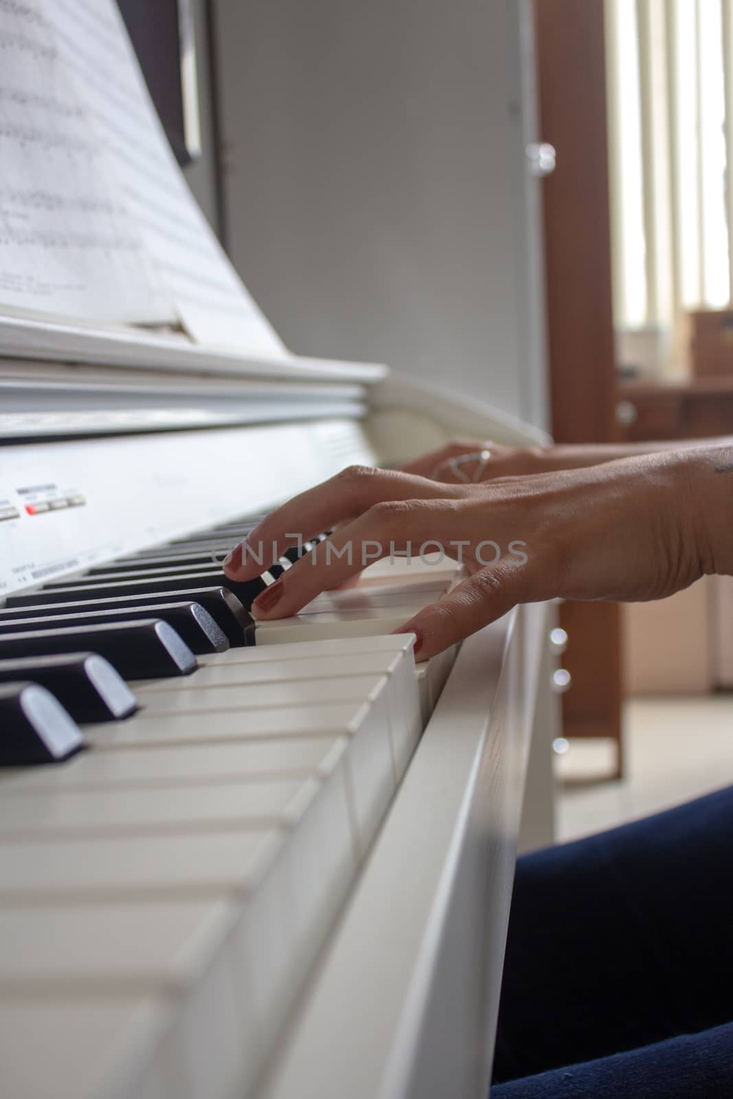 Woman practicing lessons on her white electric piano