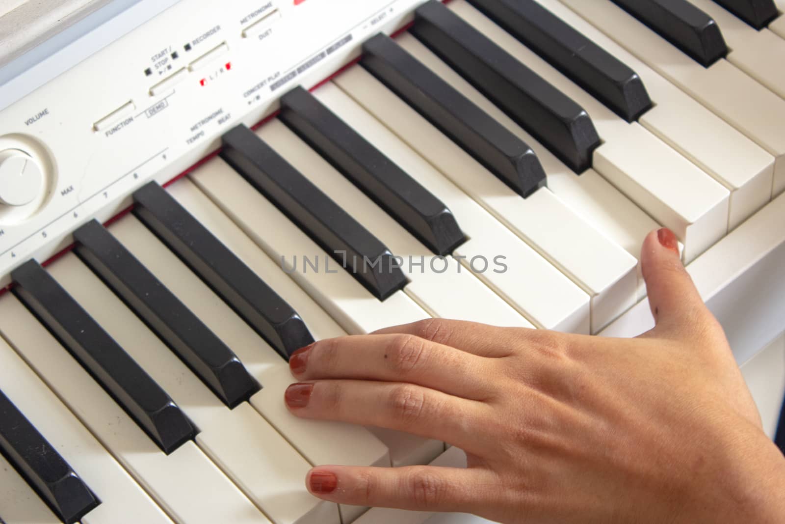 Woman practicing lessons on her white electric piano by etcho