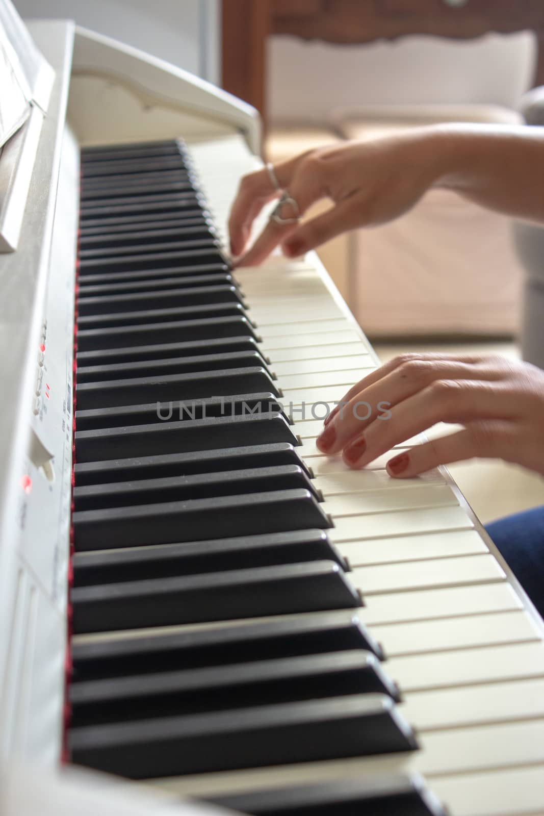 Woman practicing lessons on her white electric piano by etcho