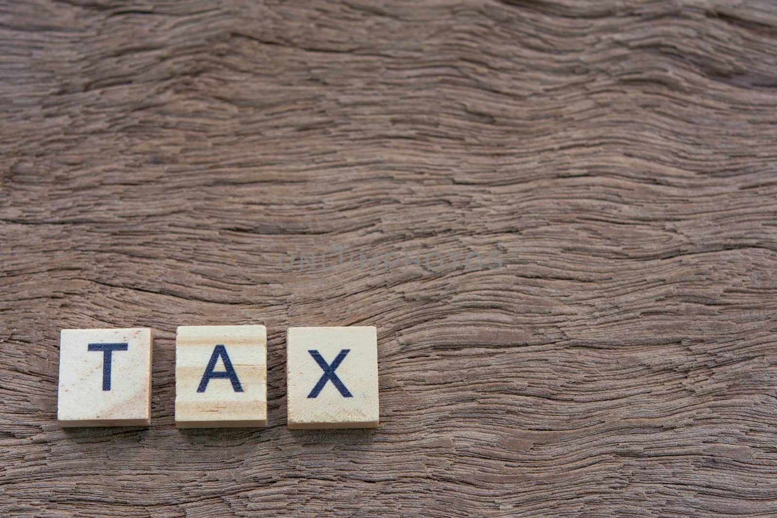 Tax with wooden alphabet blocks, on plank wooden background with copy space

