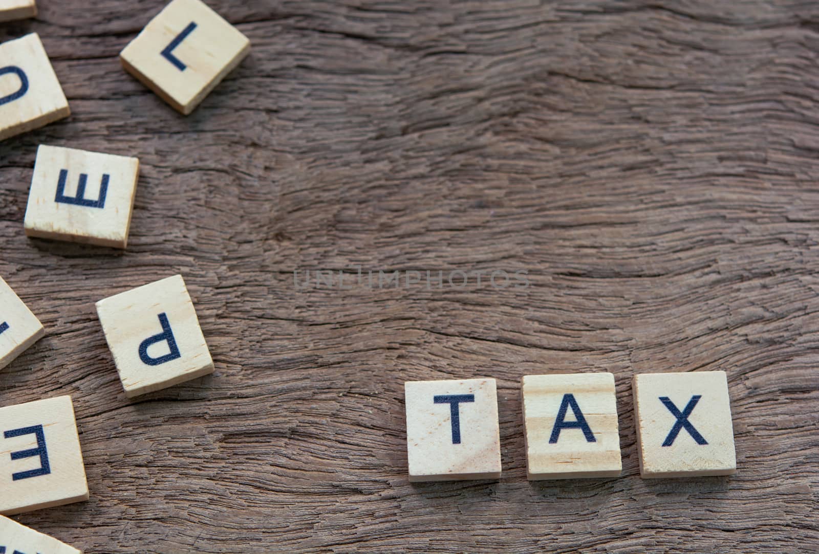 Tax with wooden alphabet blocks, on plank wooden background with copy space
