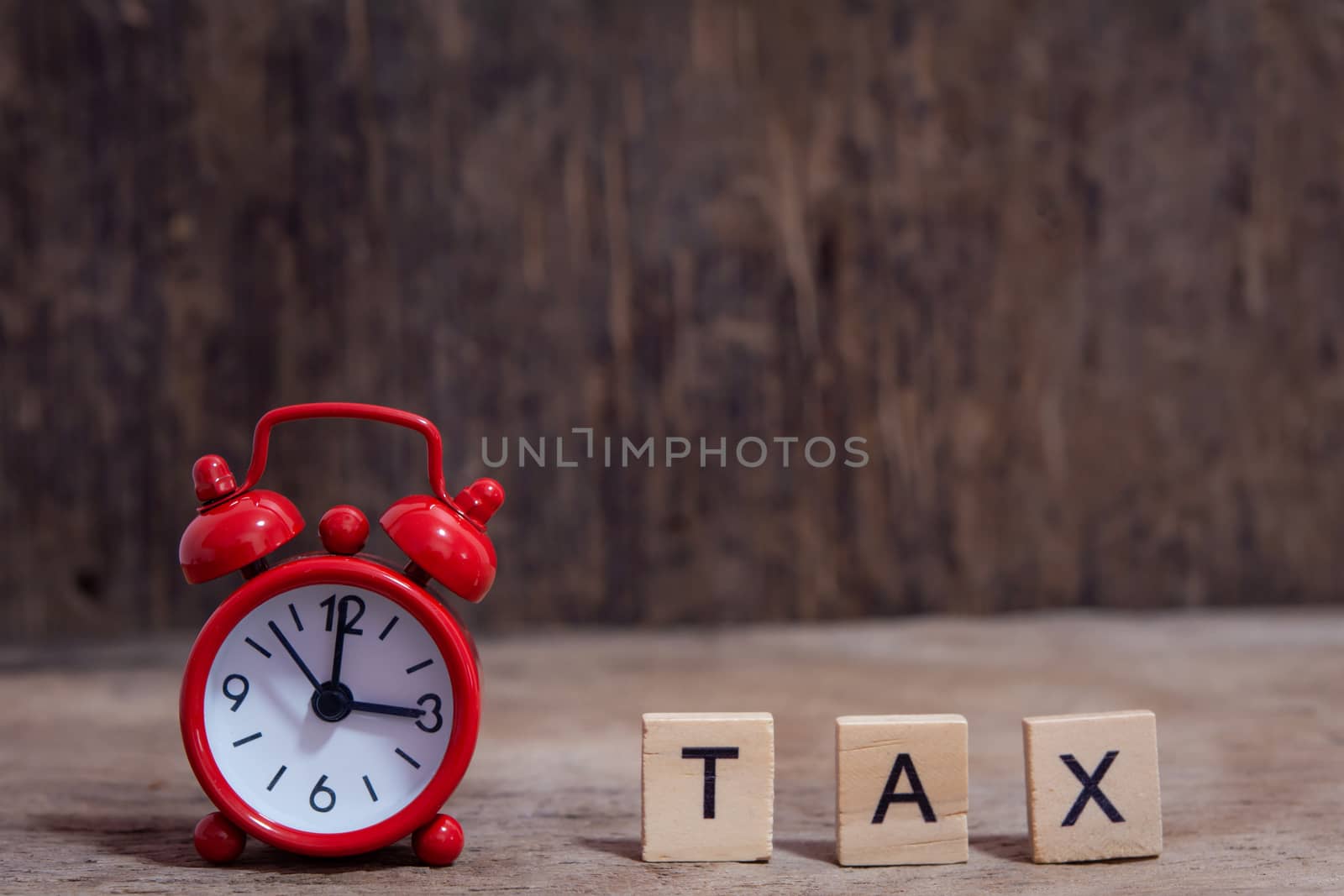 Tax with wooden alphabet blocks and Red alarm clock, on Table dark plank wooden background with copy space
