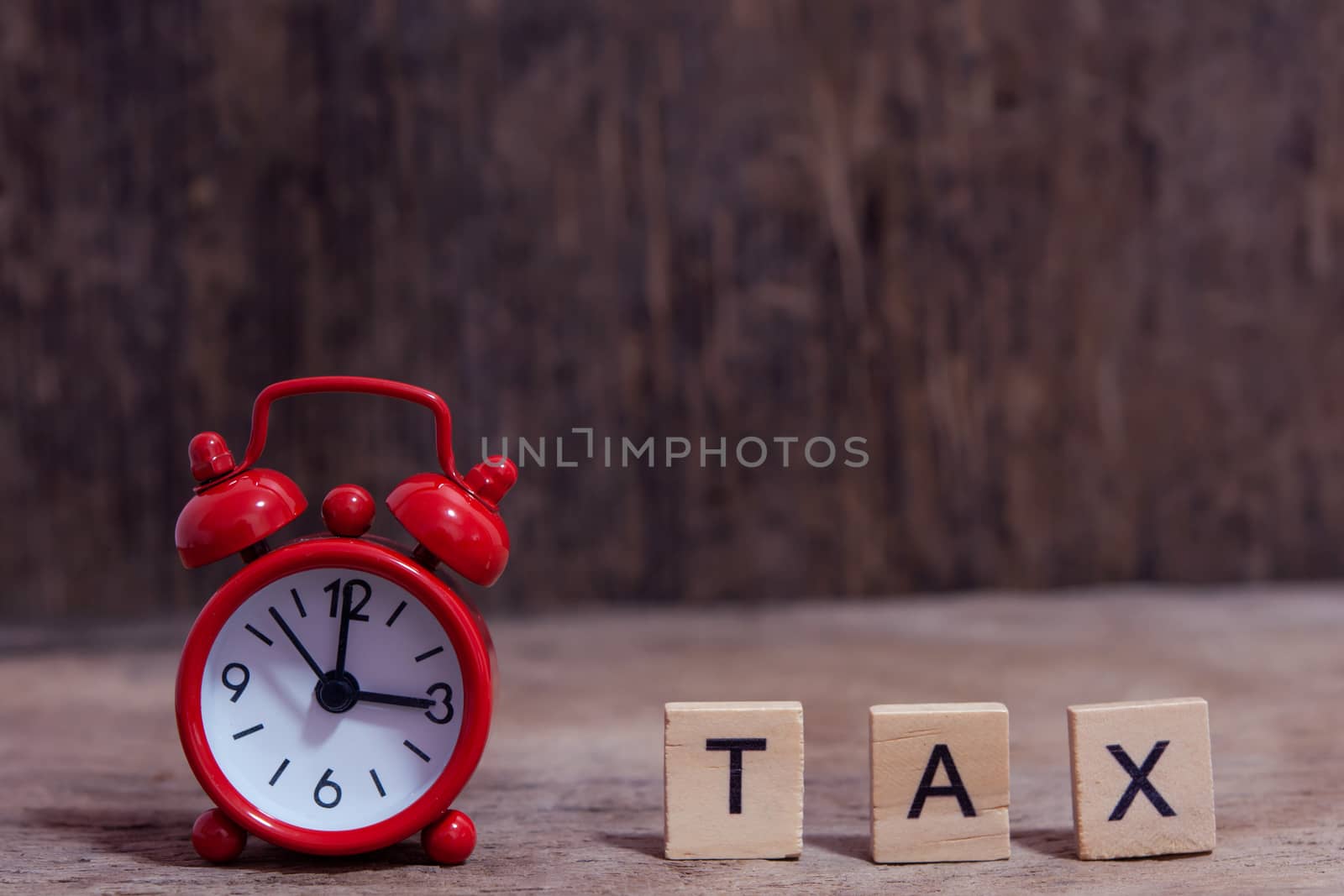 Tax with wooden alphabet blocks and Red alarm clock, on Table dark plank wooden background with copy space
