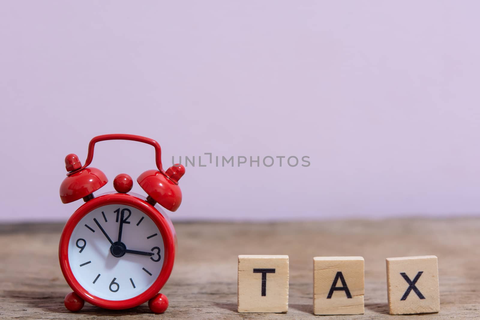 Tax with wooden alphabet blocks and Red alarm clock, on Table dark plank wooden background with copy space
