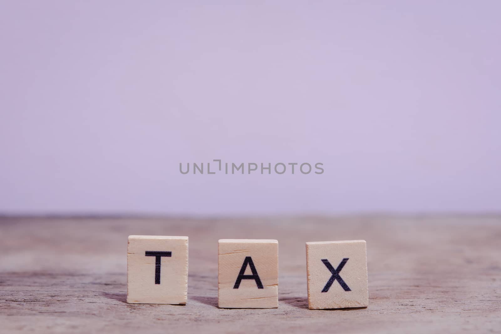 Tax with wooden alphabet blocks, on plank wooden background with copy space
