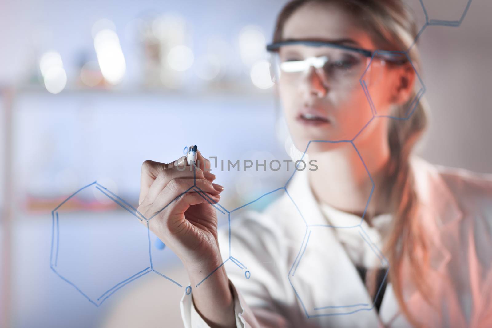 Portrait of a confident female researcher in life science laboratory writing structural chemical formula on a glass board. by kasto