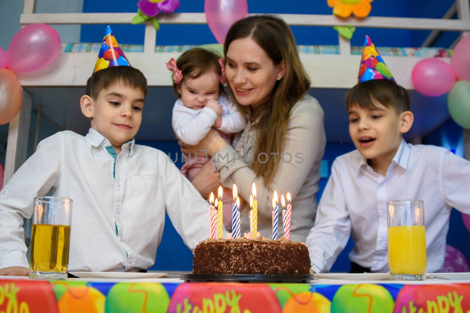 Children prepare to put out candles on a festive cake