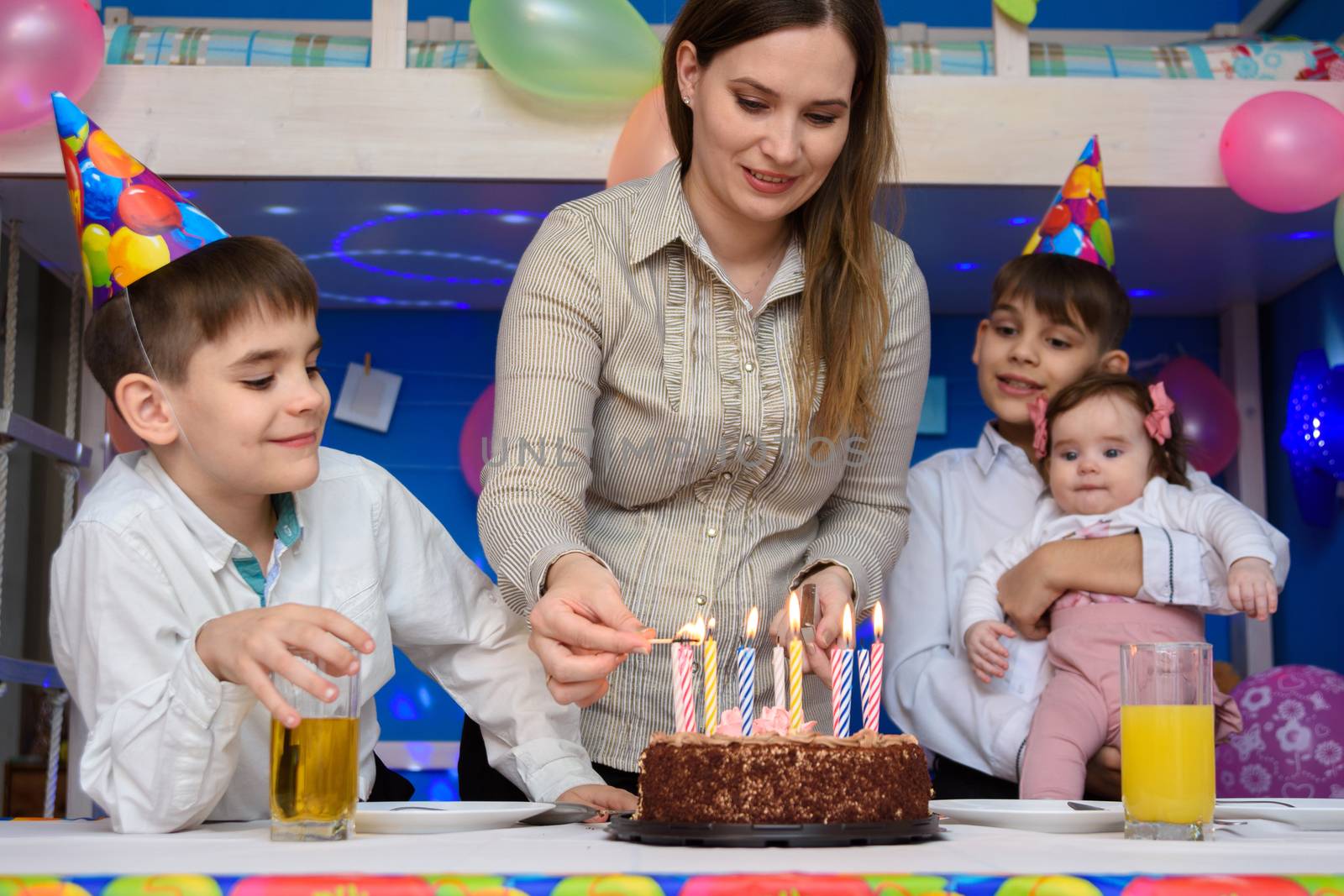 Girl lights candles on a pie at the festive table