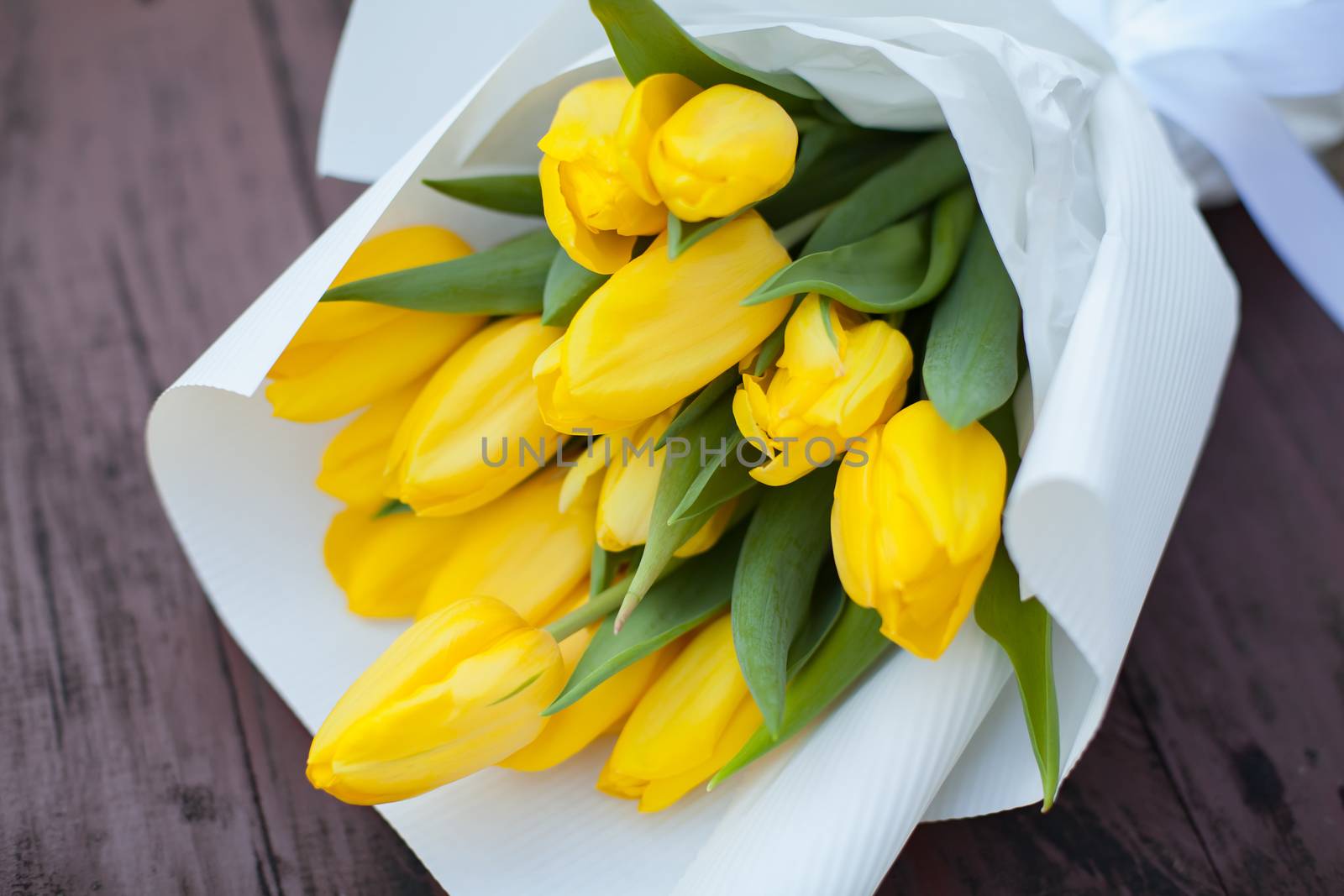 Yellow tulips bouquet over wooden table