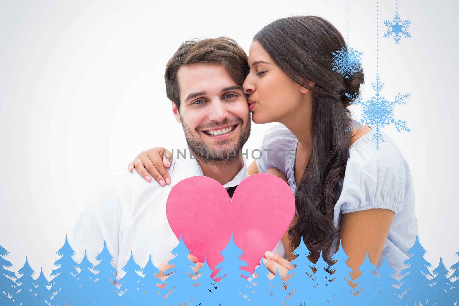 Pretty brunette giving boyfriend a kiss and her heart against snowflakes and fir trees in blue
