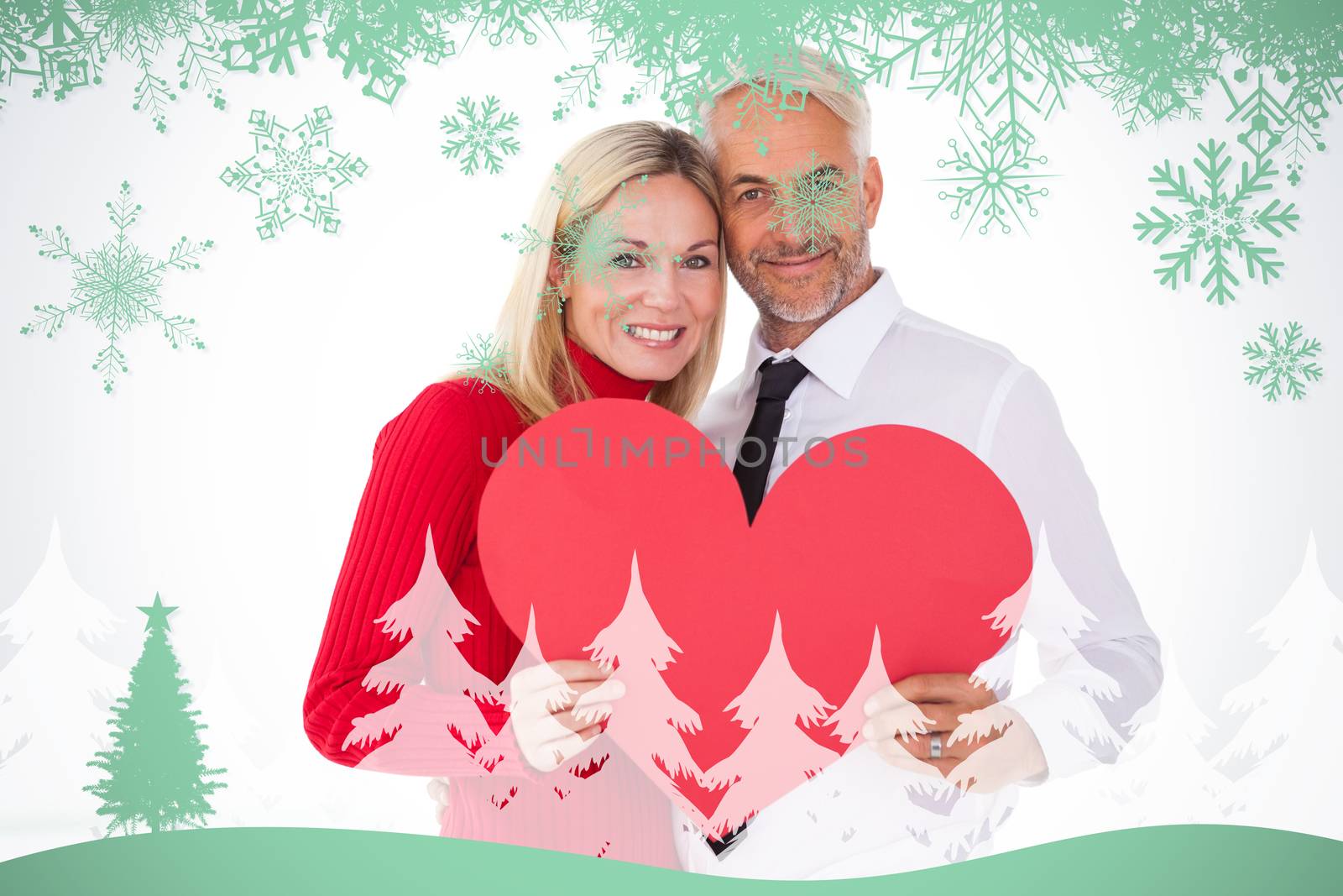 Handsome man getting a heart card form wife against snowflakes and fir tree in green