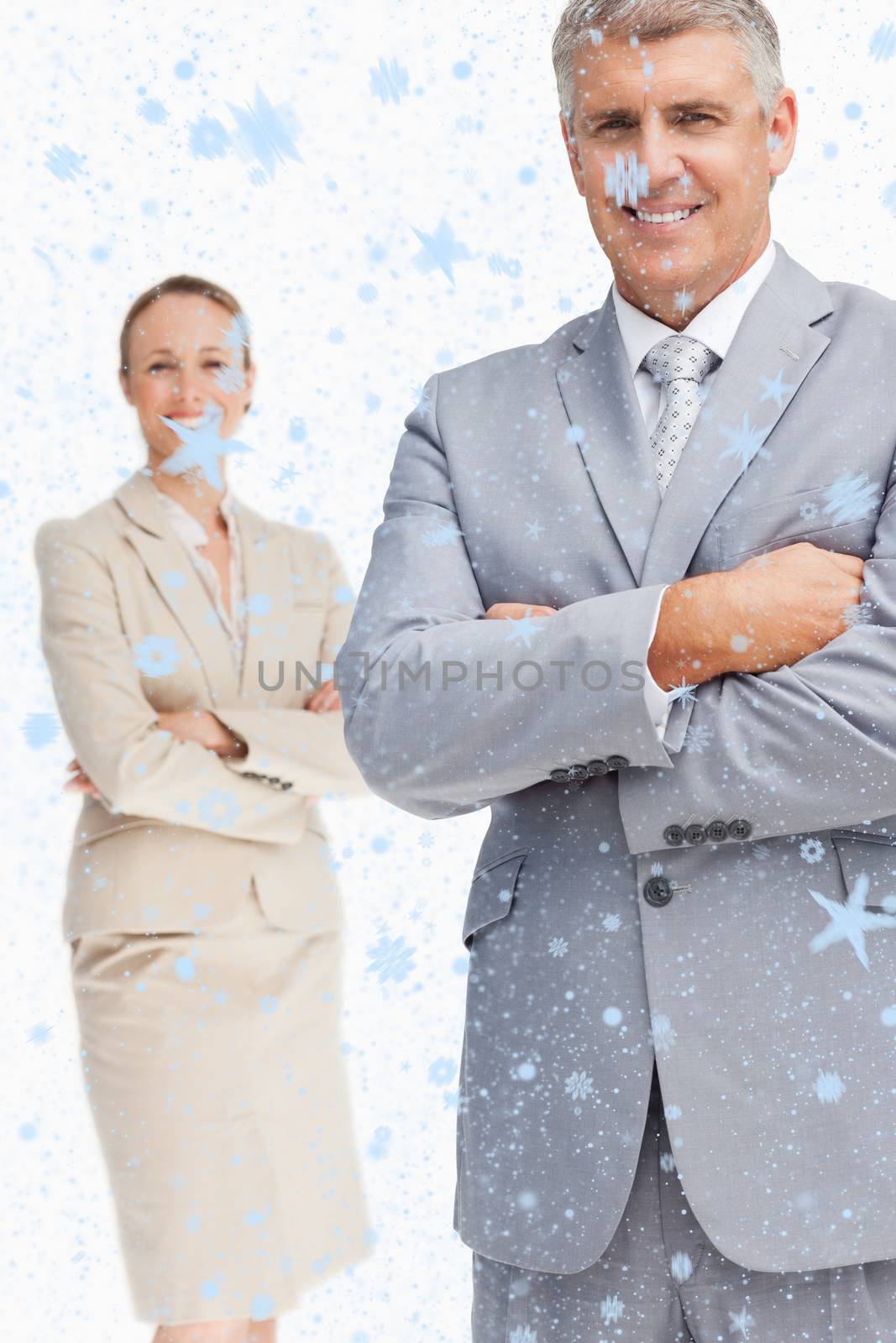 Cheerful business people with folded arms against snow falling