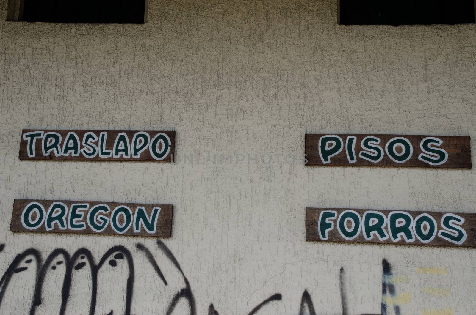 Products advertised for sale and grafitti in a wall. Puerto Montt. Los Lagos Region. Chile.