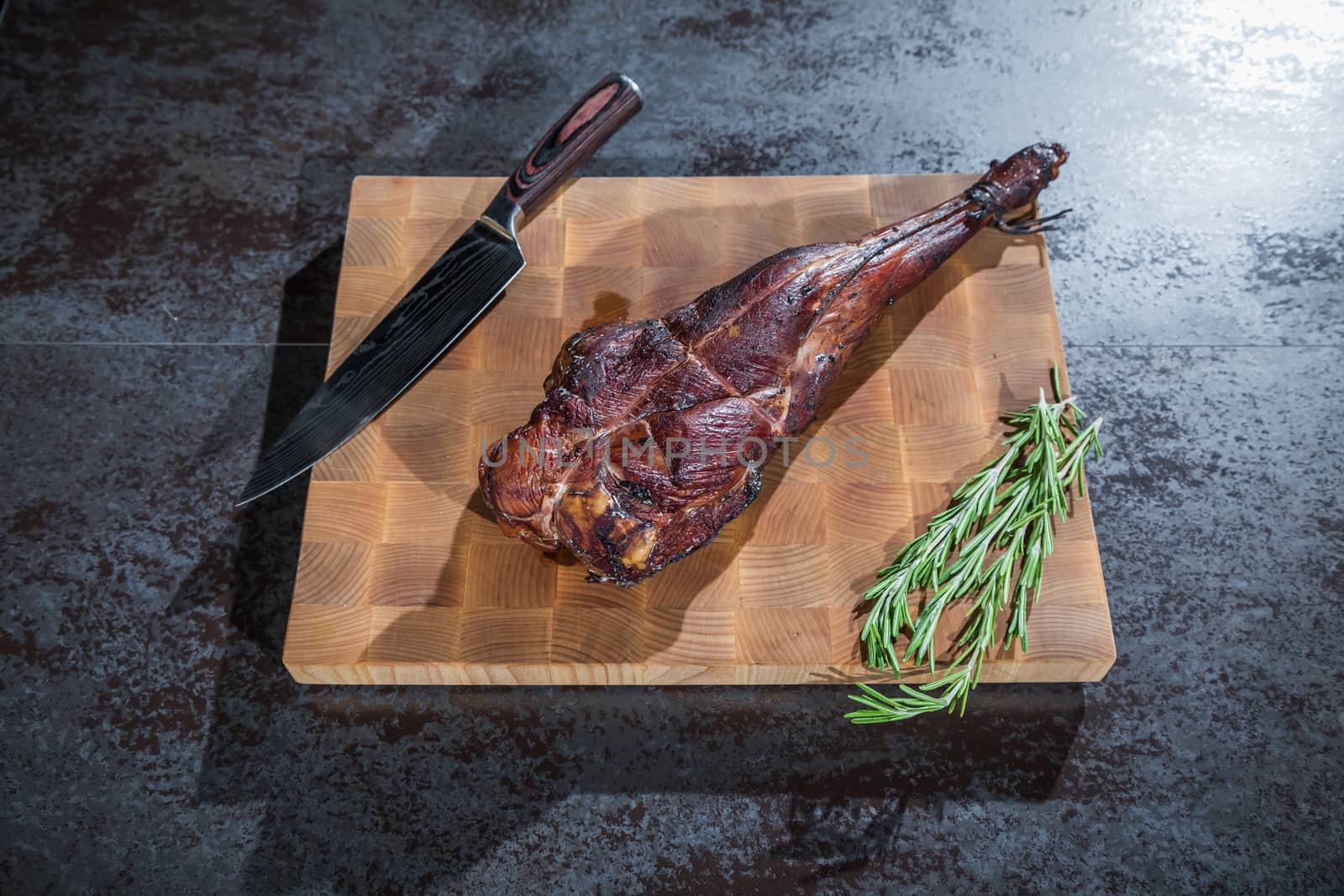 Smoked lamb leg on a wooden board with a knife by sveter