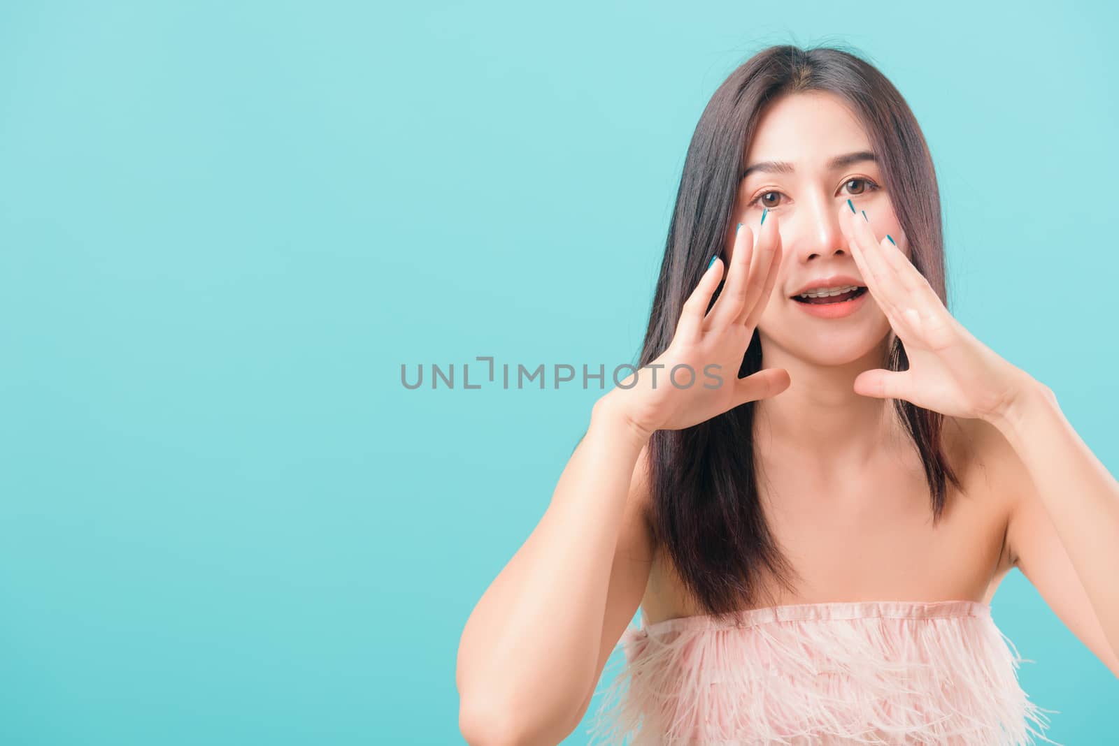 Asian happy portrait beautiful young woman standing smiling big shout out with hands next mouth and looking to camera isolated on blue background with copy space for text