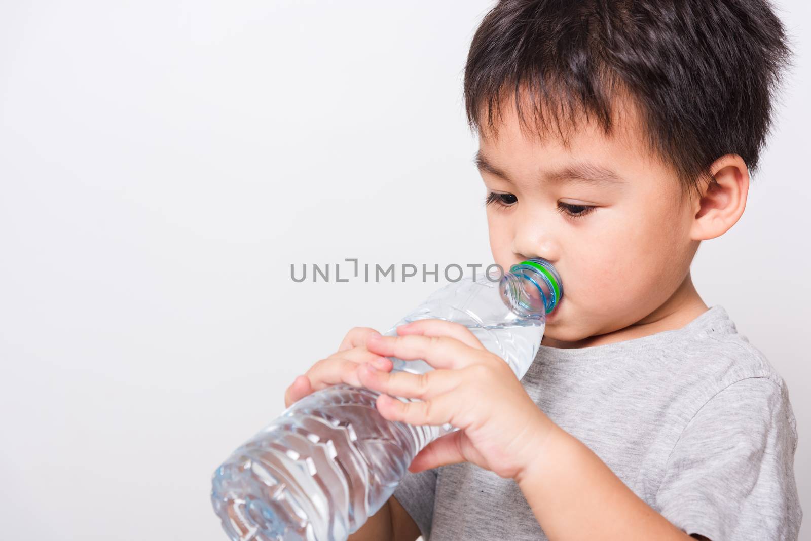 Closeup Asian face, Little children boy drinking water from Plastic bottle on white background with copy space, health medical care