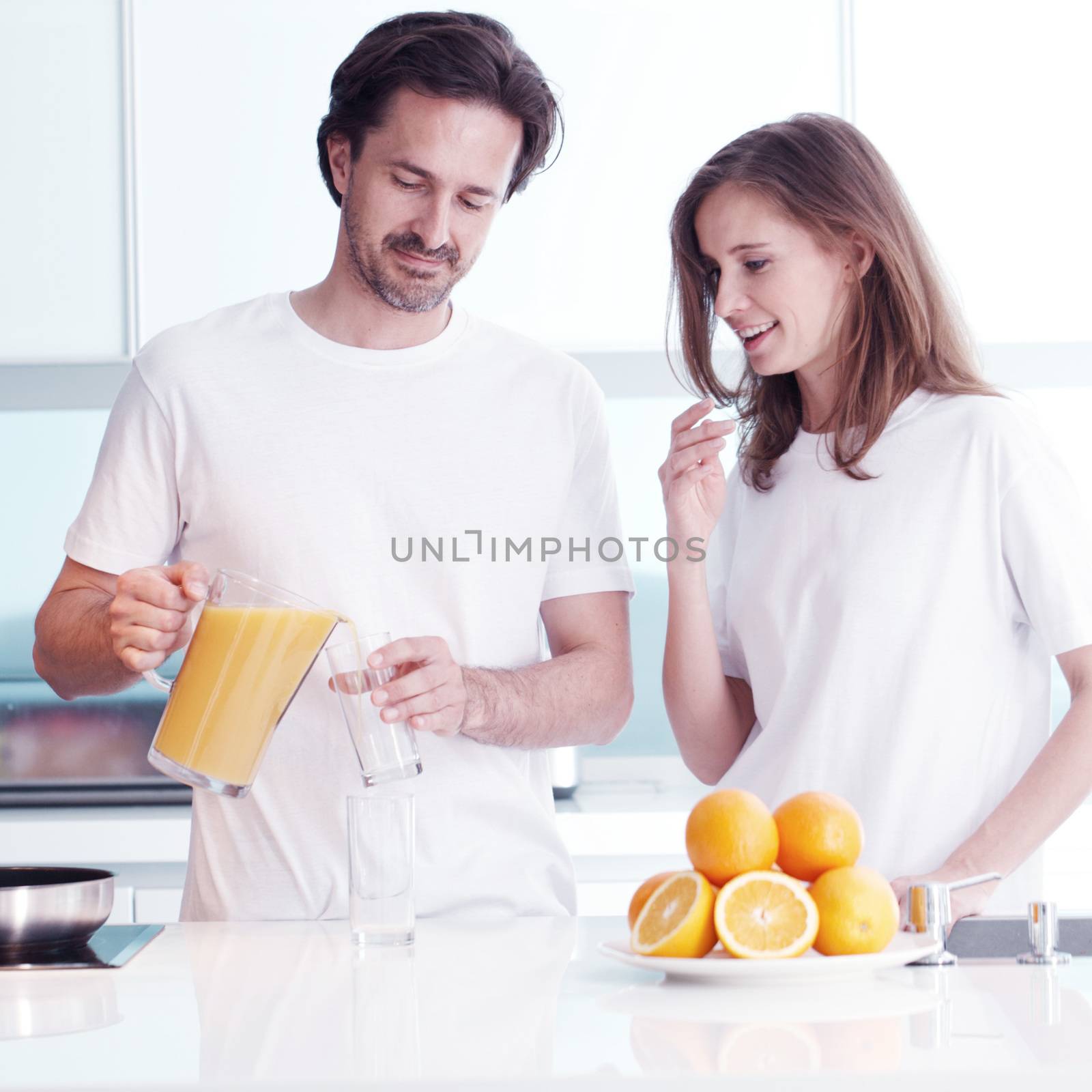 Couple making fresh orange juice at kitchen in the morning