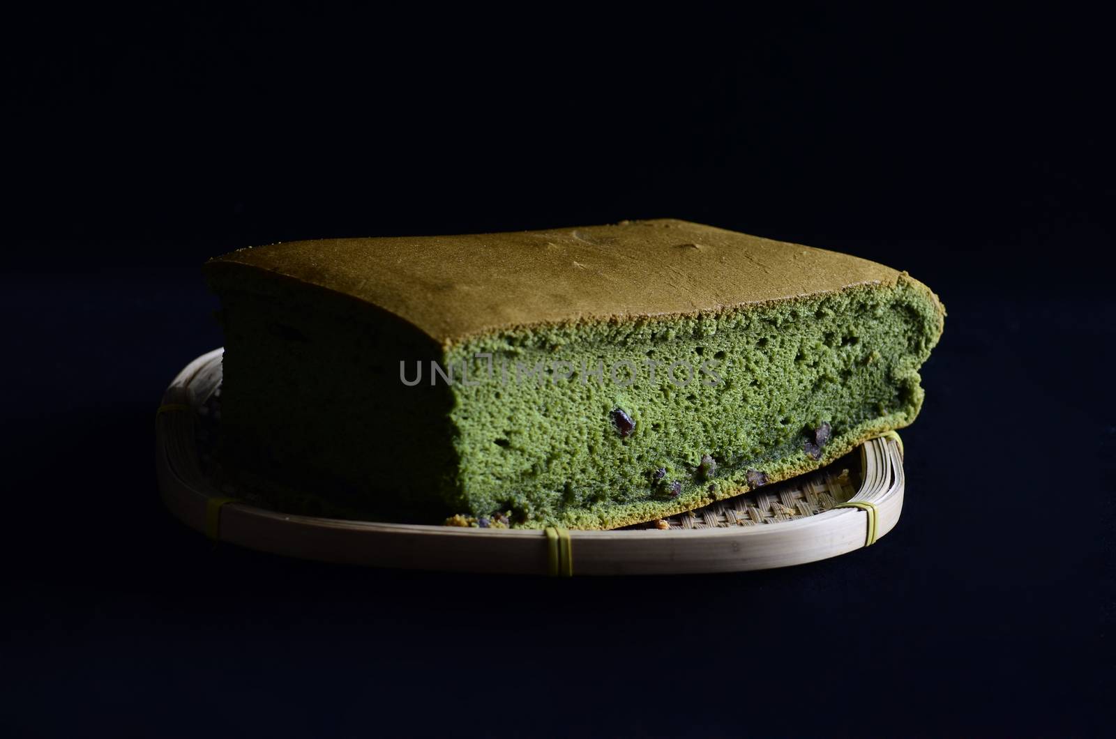 Matcha sponge cake  on wooden basket isolated on black background