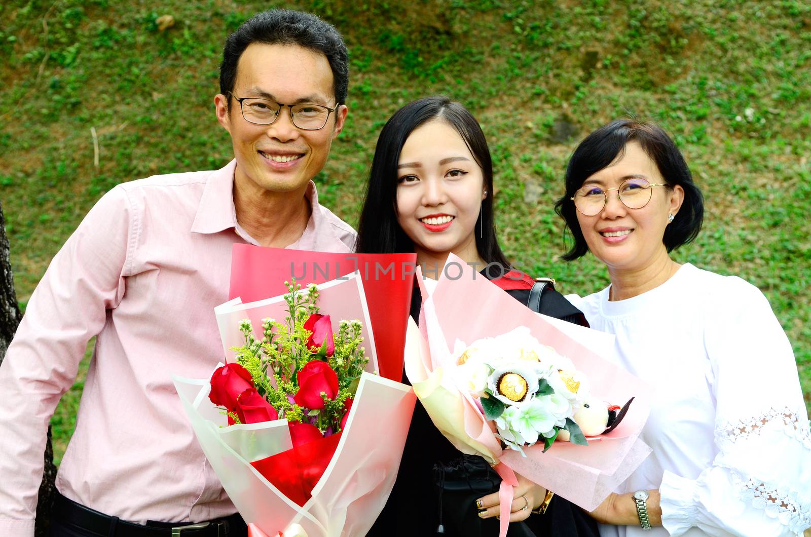 Asian university student and family celebrating graduation outdoor