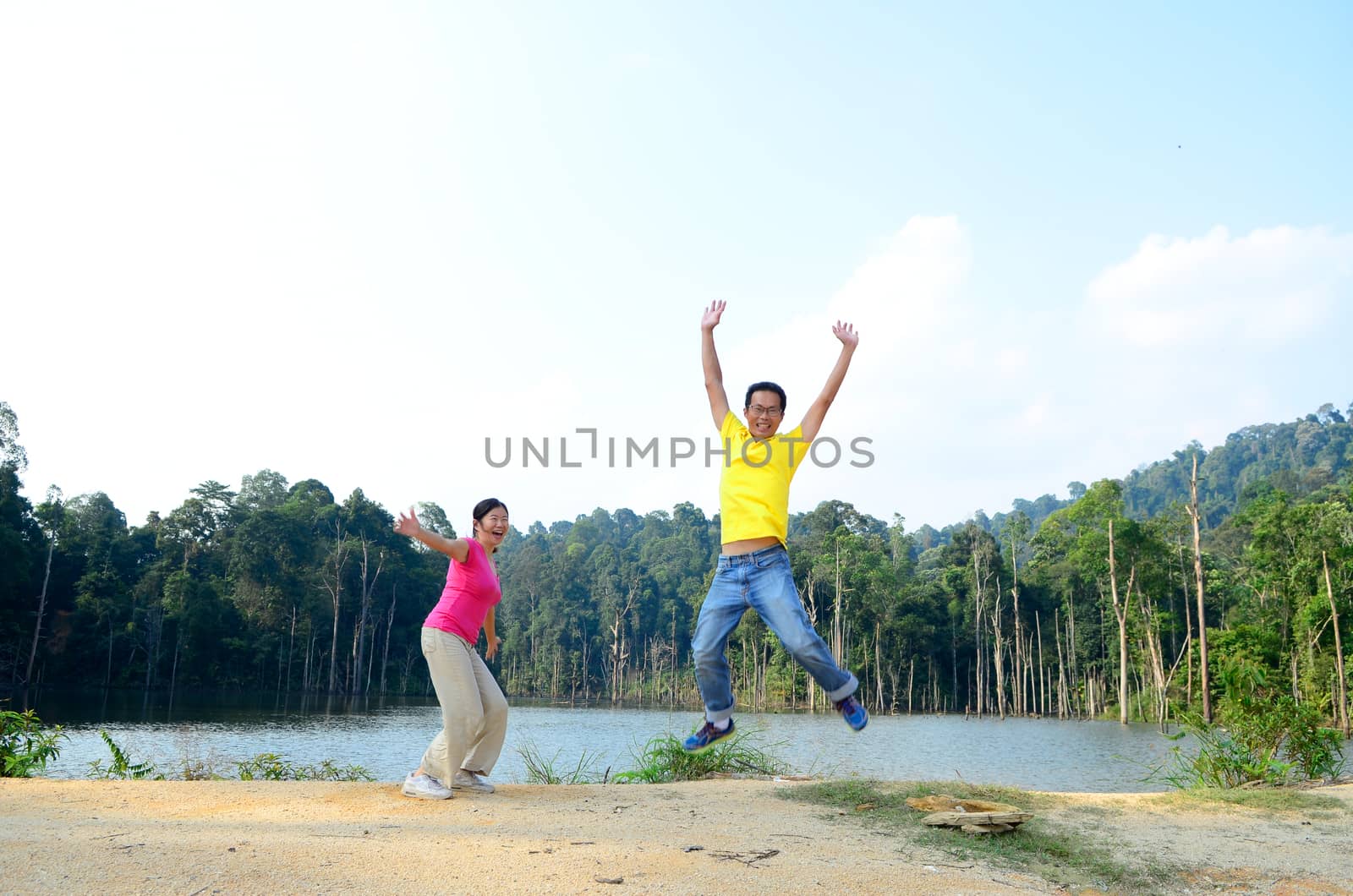Asian couple jumping with joy by a lake
