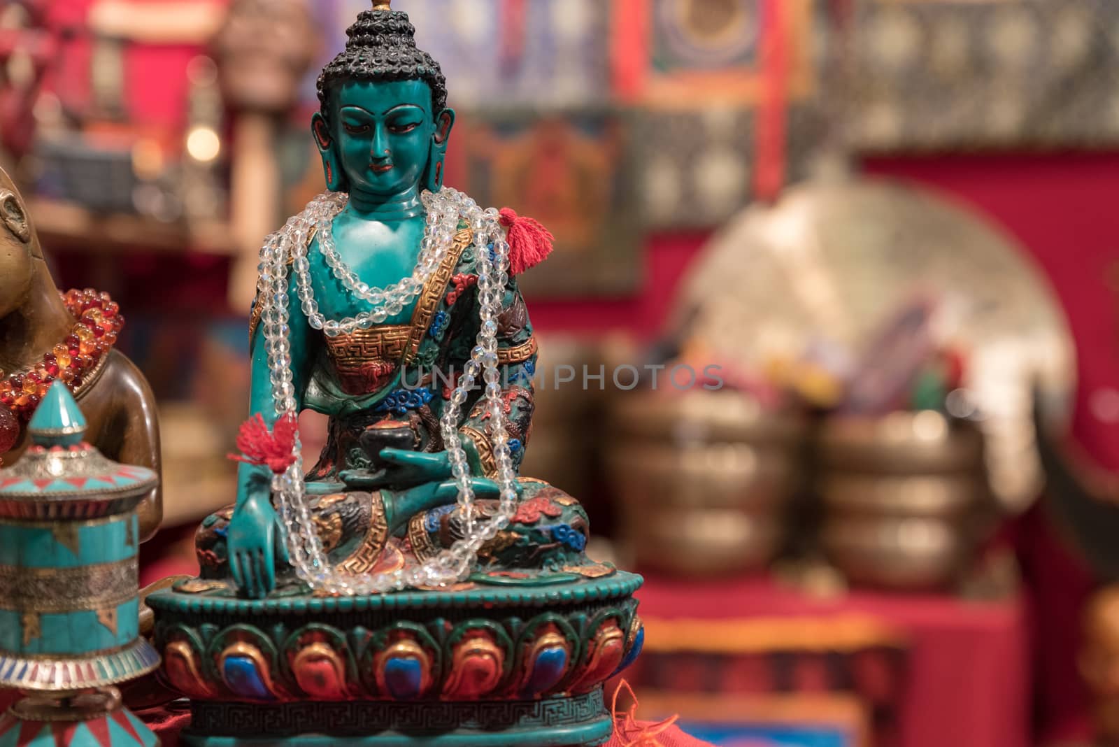 Buddha statuette with votive necklace exposed in an Asian market, horizontal image with shaded background