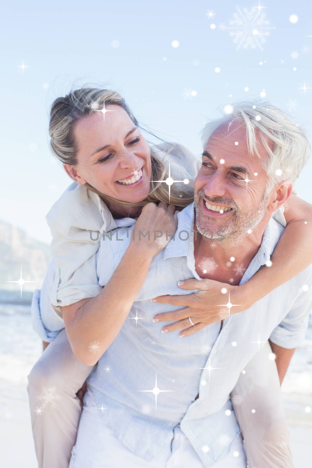 Man giving his smiling wife a piggy back at the beach against snow falling