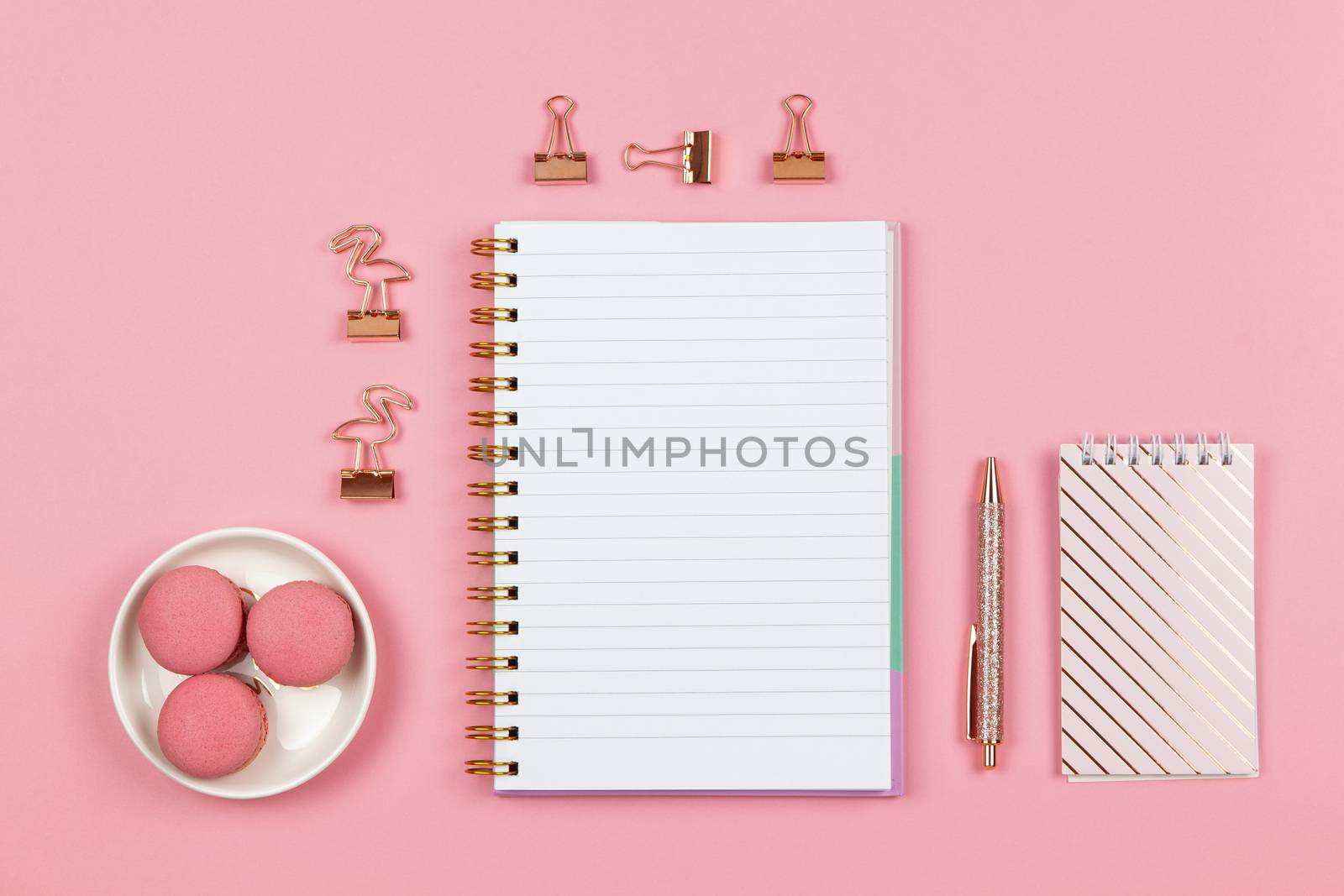 Modern female working space, top view. Notebooks, pen, clamps on pink backround, copy space, flat lay. Desktop of freelancer, student. Work from home, back to school, education concept. Horizontal.