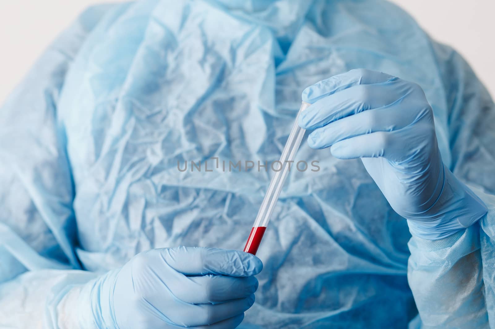 Close up of doctor hand holding blood sample. Medical equipment. Blood test. A doctor wearing personal protective equipment including mask, goggle, and suit to protect COVID 19 coronavirus infection.