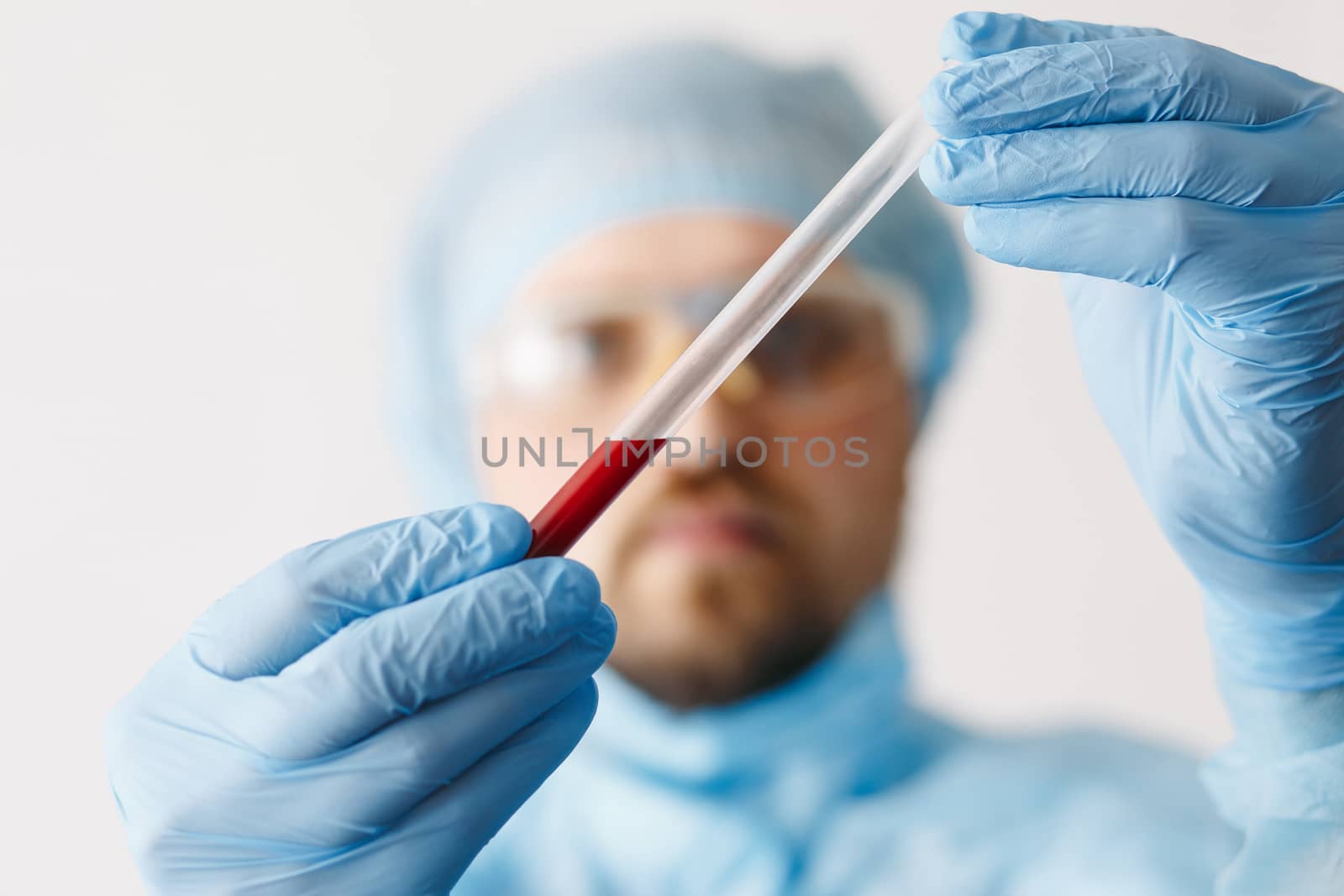 Close up of doctor hand holding blood sample. Medical equipment. Blood test. A doctor wearing personal protective equipment including mask, goggle, and suit to protect COVID 19 coronavirus infection.