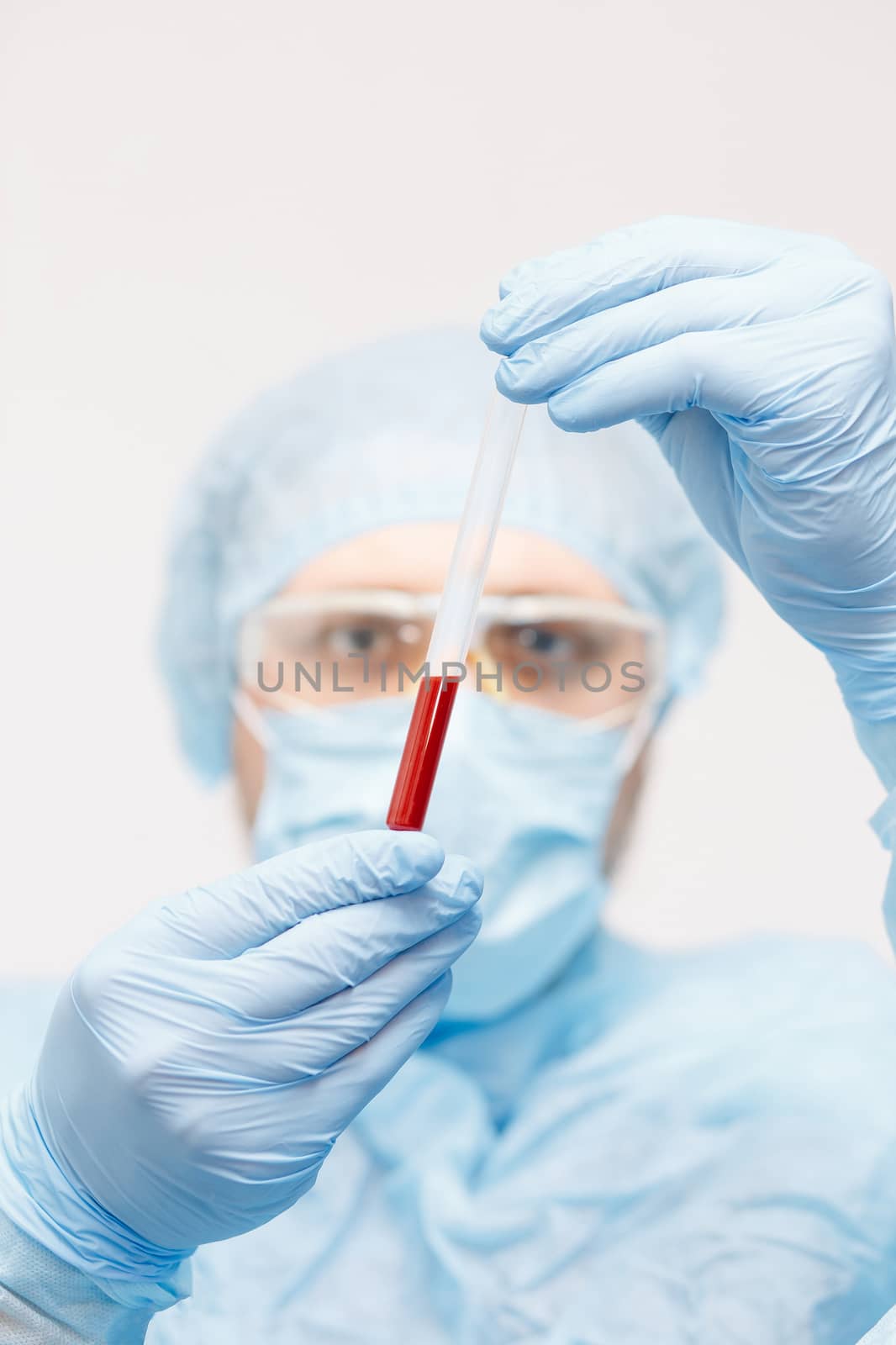 Close up of doctor hand holding blood sample. Medical equipment. Blood test. A doctor wearing personal protective equipment including mask, goggle, and suit to protect COVID 19 coronavirus infection.