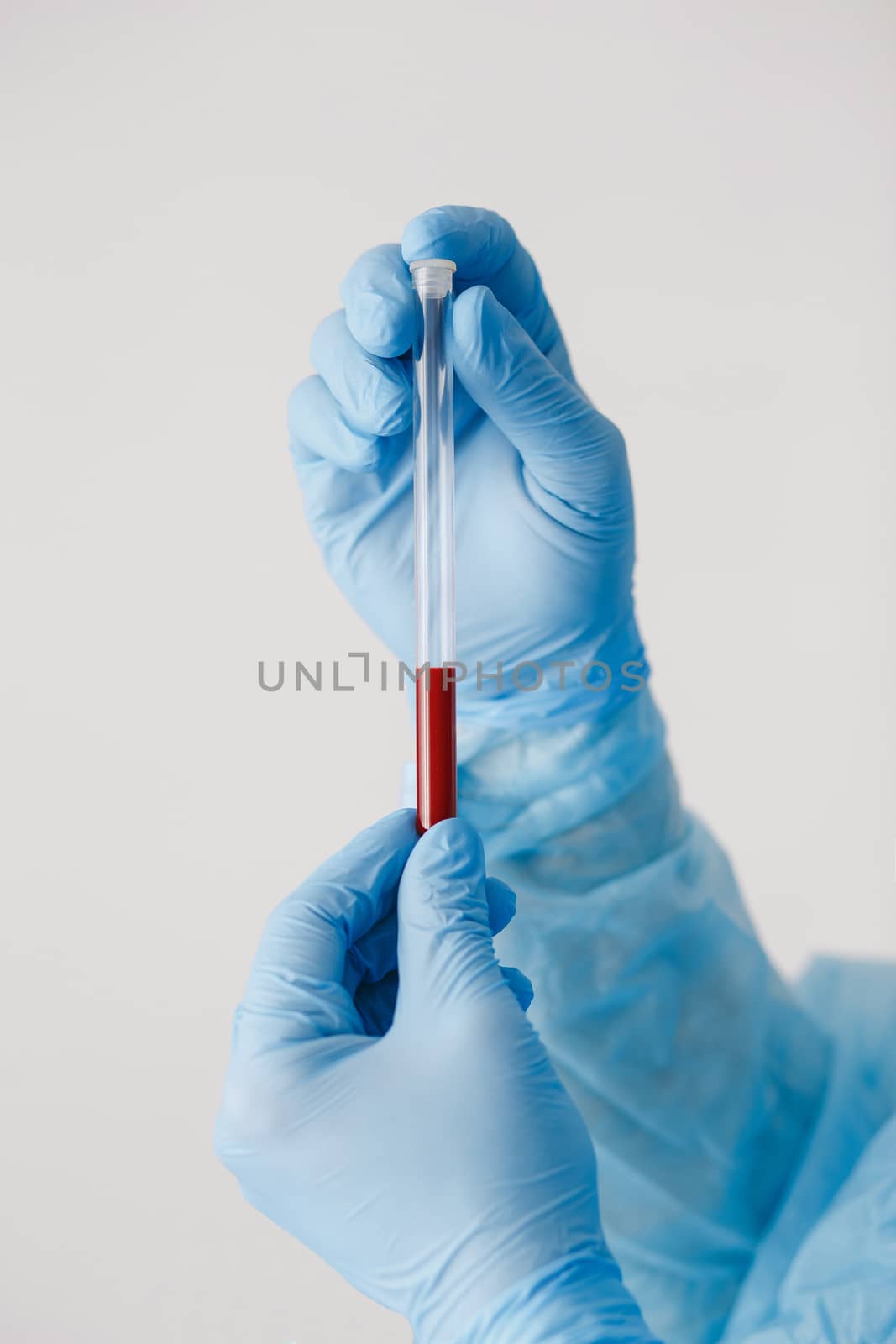 Close up of doctor hand holding blood sample. Medical equipment. Blood test. A doctor wearing personal protective equipment including mask, goggle, and suit to protect COVID 19 coronavirus infection.