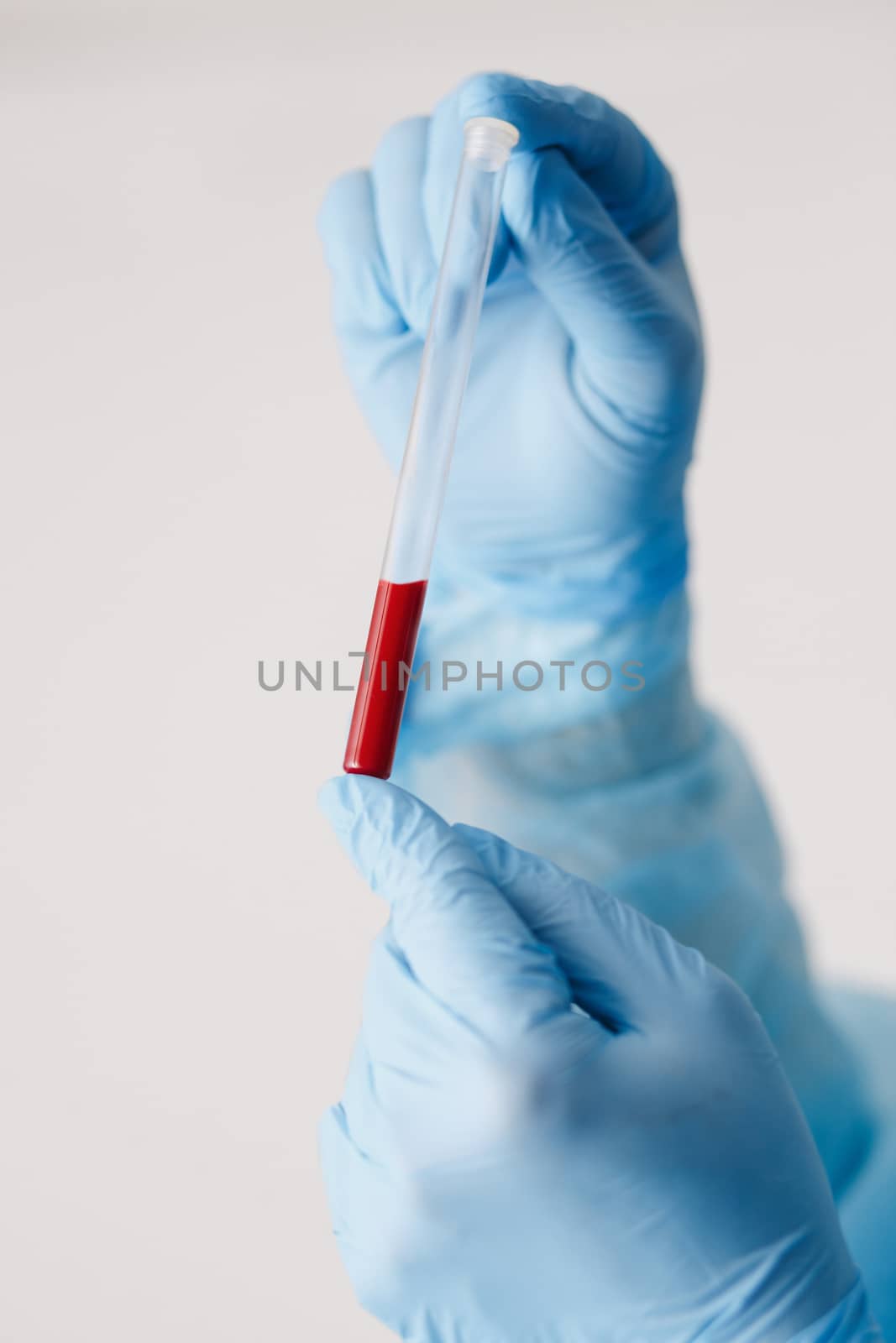 Close up of doctor hand holding blood sample. Medical equipment. Blood test. A doctor wearing personal protective equipment including mask, goggle, and suit to protect COVID 19 coronavirus infection.