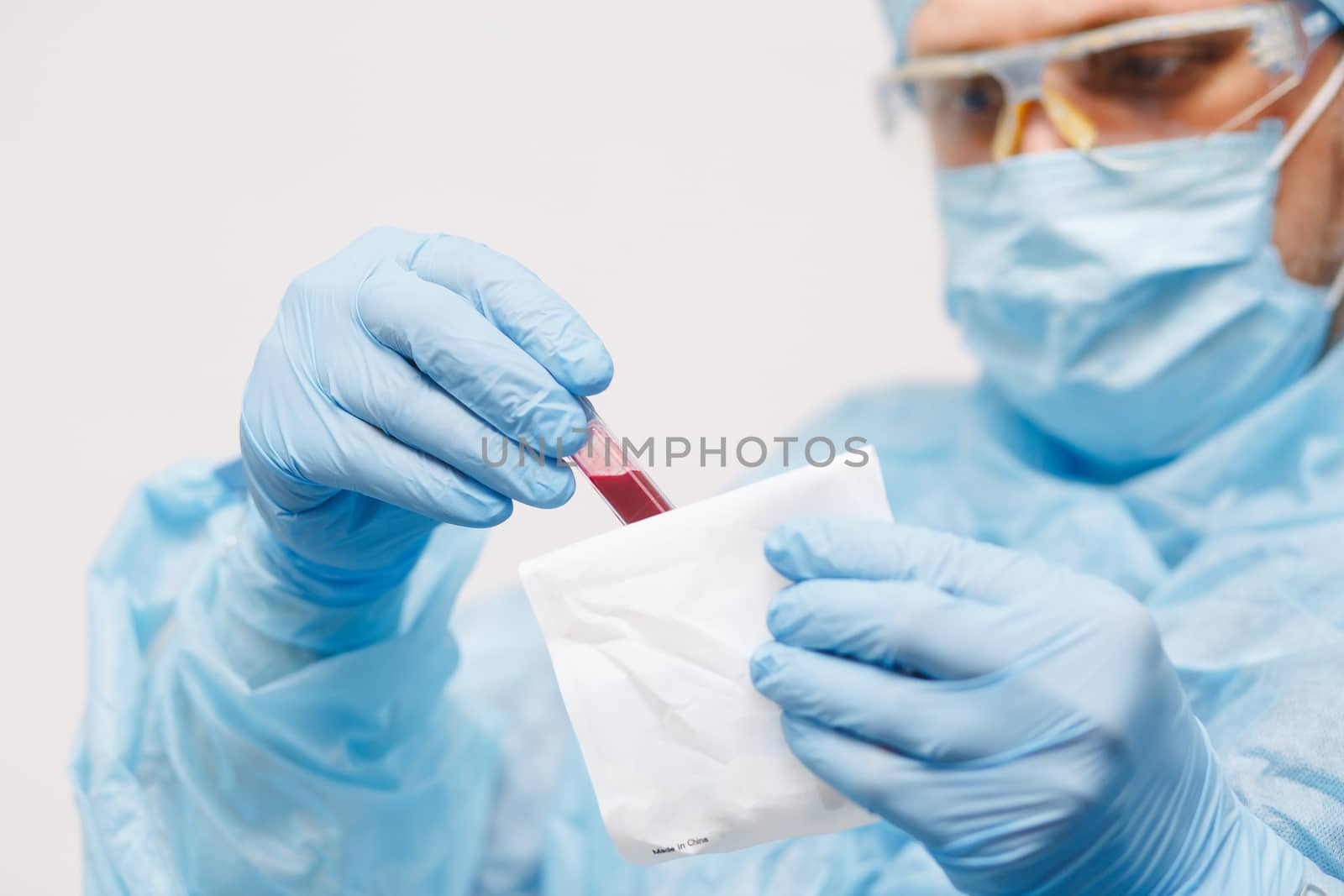 Close up of doctor hand holding blood sample. Medical equipment. Blood test. A doctor wearing personal protective equipment including mask, goggle, and suit to protect COVID 19 coronavirus infection.