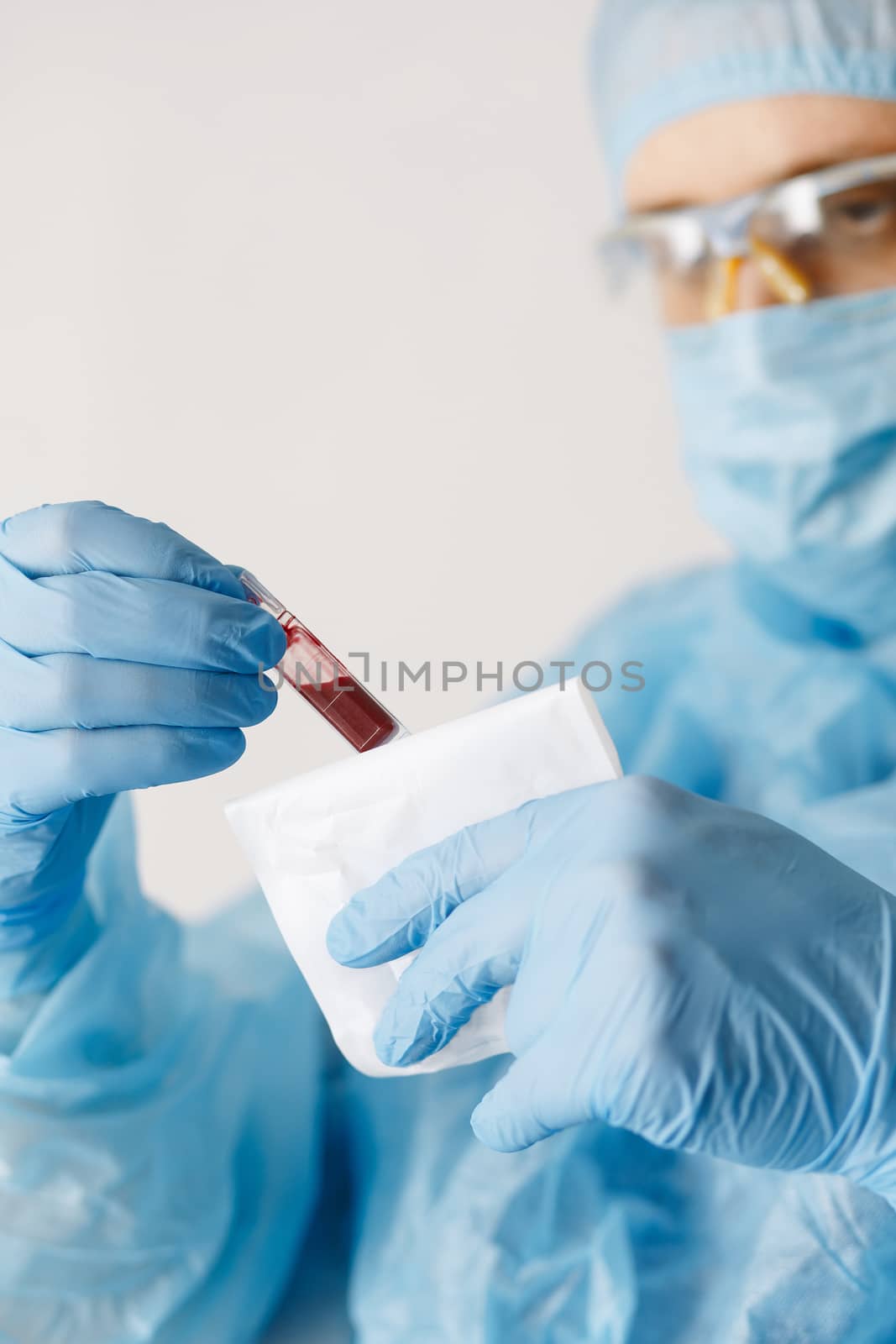 Close up of doctor hand holding blood sample. Medical equipment. Blood test. A doctor wearing personal protective equipment including mask, goggle, and suit to protect COVID-19 coronavirus infection. by Denys_N