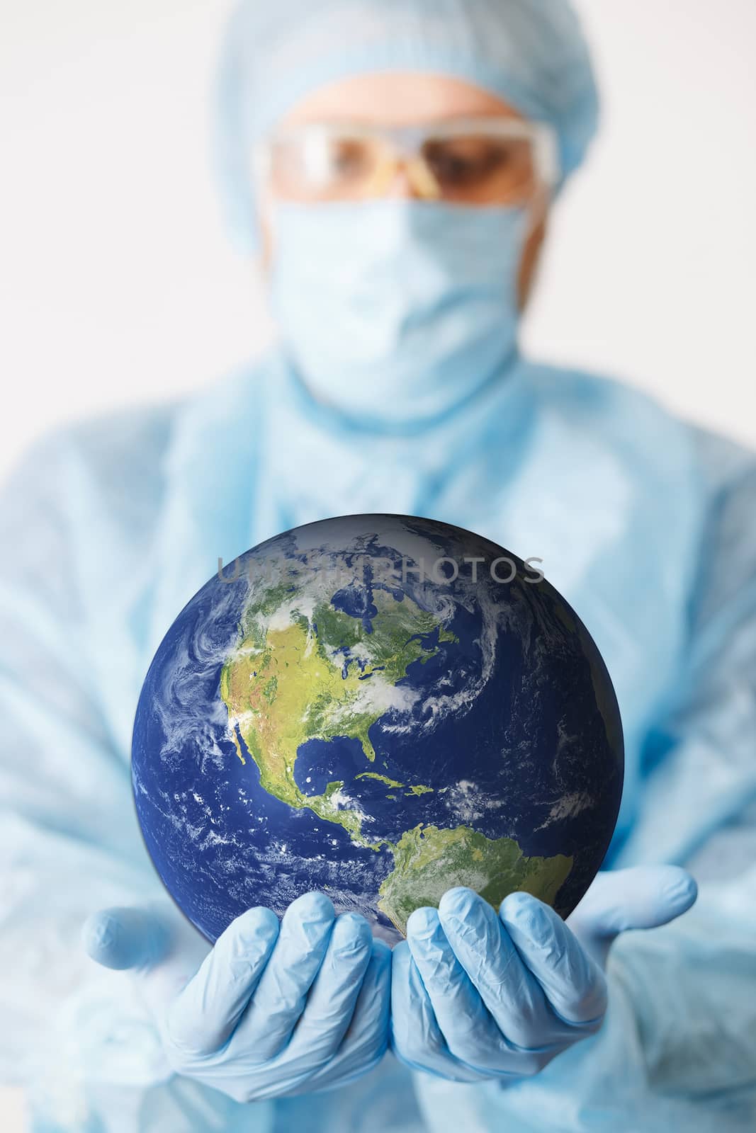 Close up of doctor hand holding earth. Mock up. Medical equipment. A doctor wearing personal protective equipment including mask, goggle, and suit to protect COVID-19 coronavirus infection. by Denys_N