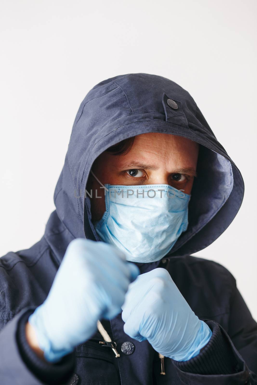 Man in hood with mask to protect him from Coronavirus in boxing pose. Corona virus pandemic. Young man with medical mask isolated. Person in hood with medical mask. COVID-19