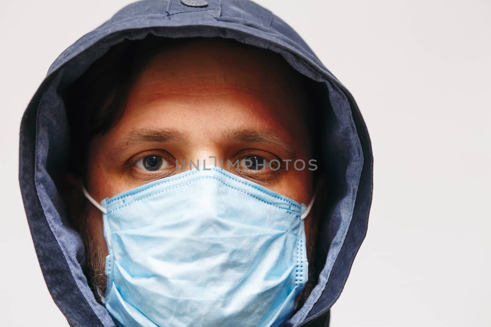 Man in hood with mask to protect him from Coronavirus. Corona virus pandemic. Young man with medical mask isolated. Person in hood with medical mask. COVID 19